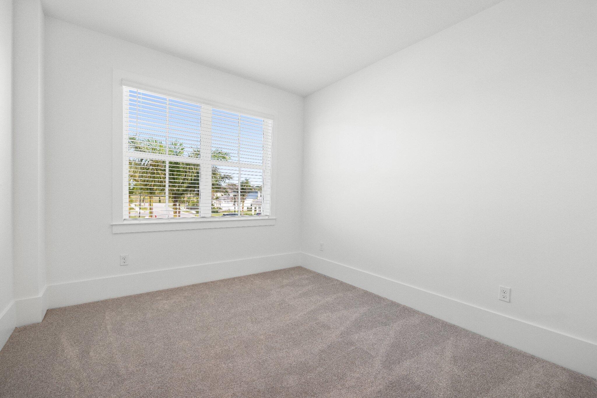 Neutral-toned carpeting, crisp white walls, and a large multi-pane window with adjustable blinds
