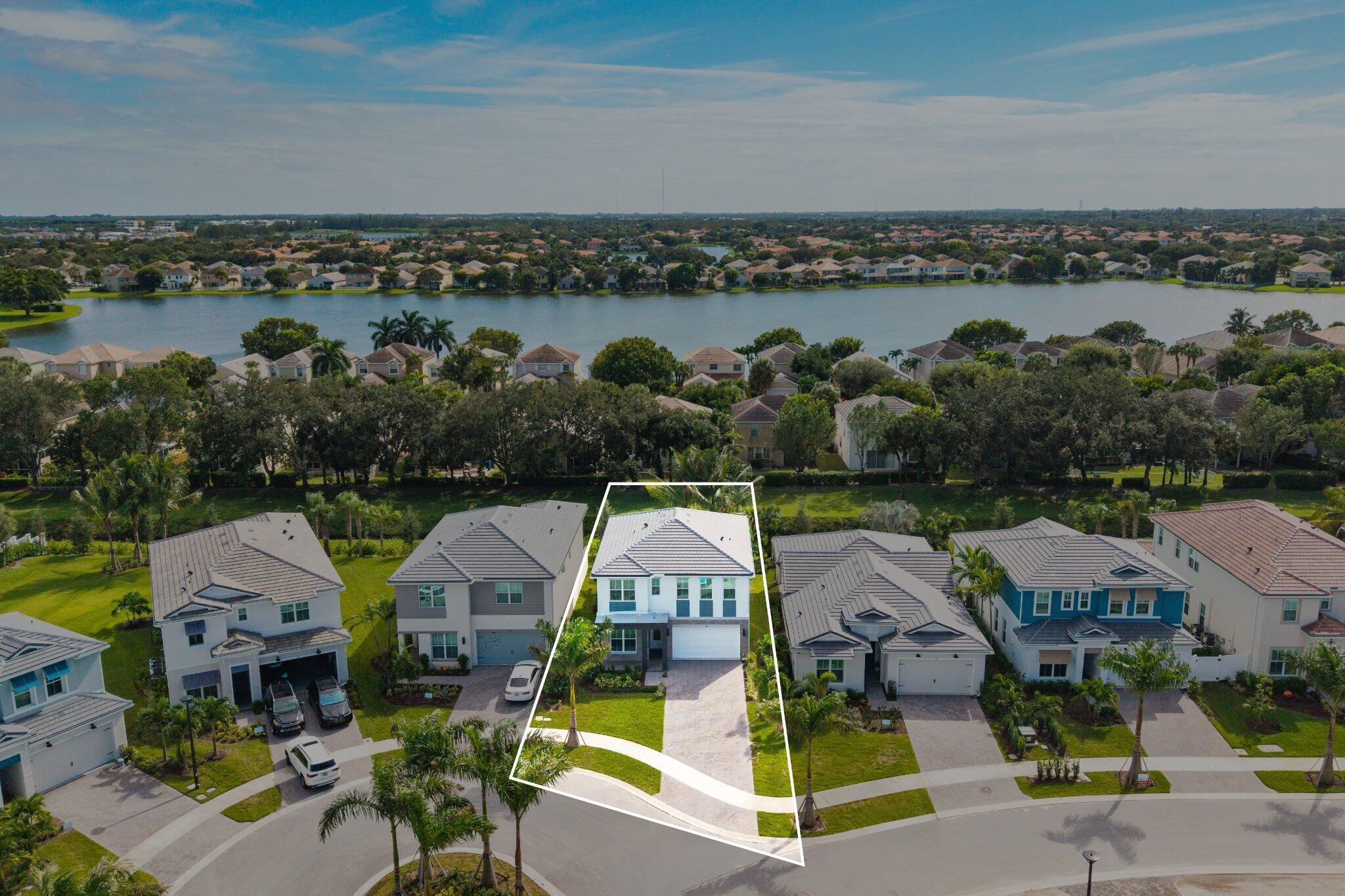 Two-story residence featuring a tile roof, paver driveway, attached two-car garage, and a waterfront lot location