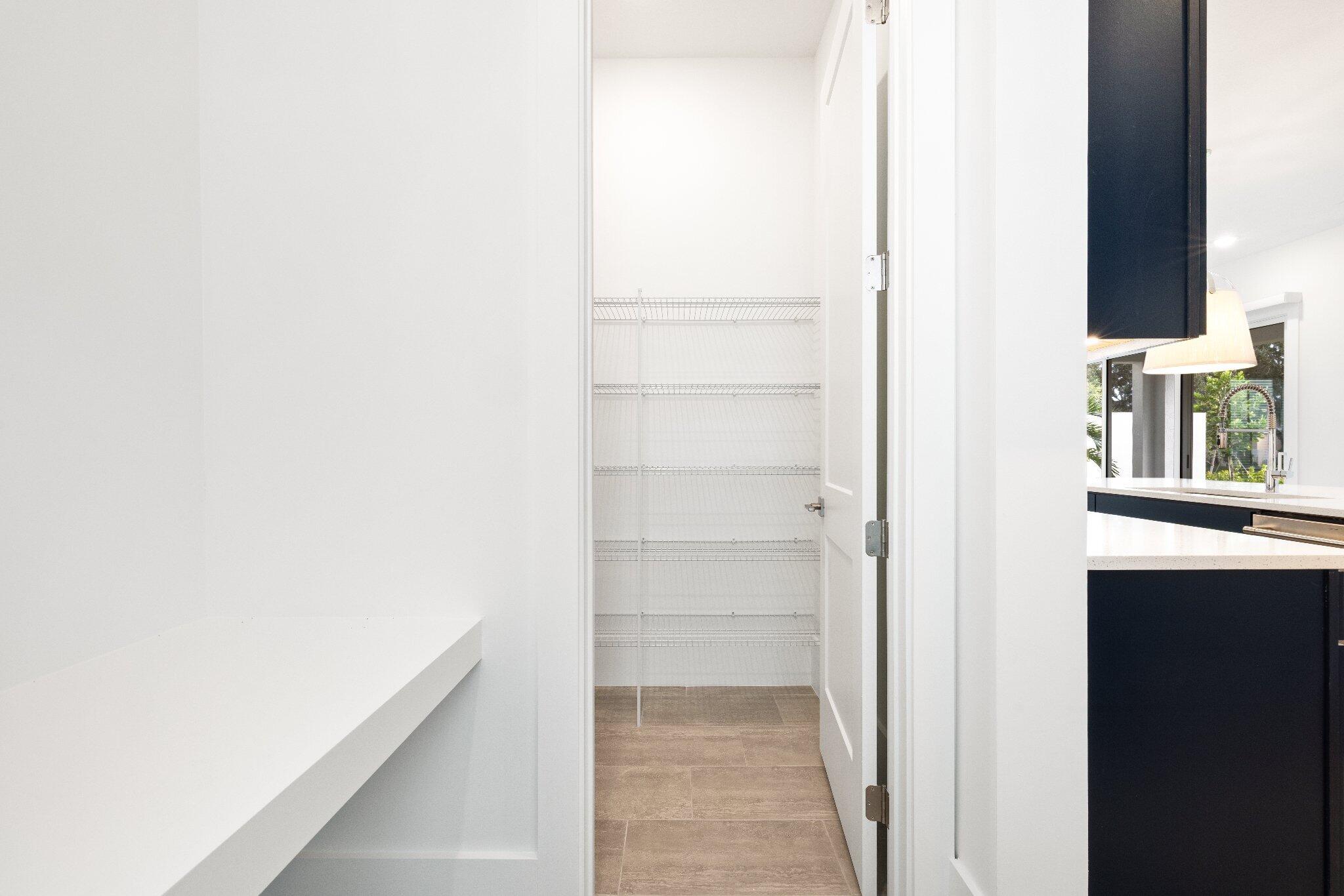 Storage space featuring tiered wire shelving, a swinging door, and tile flooring