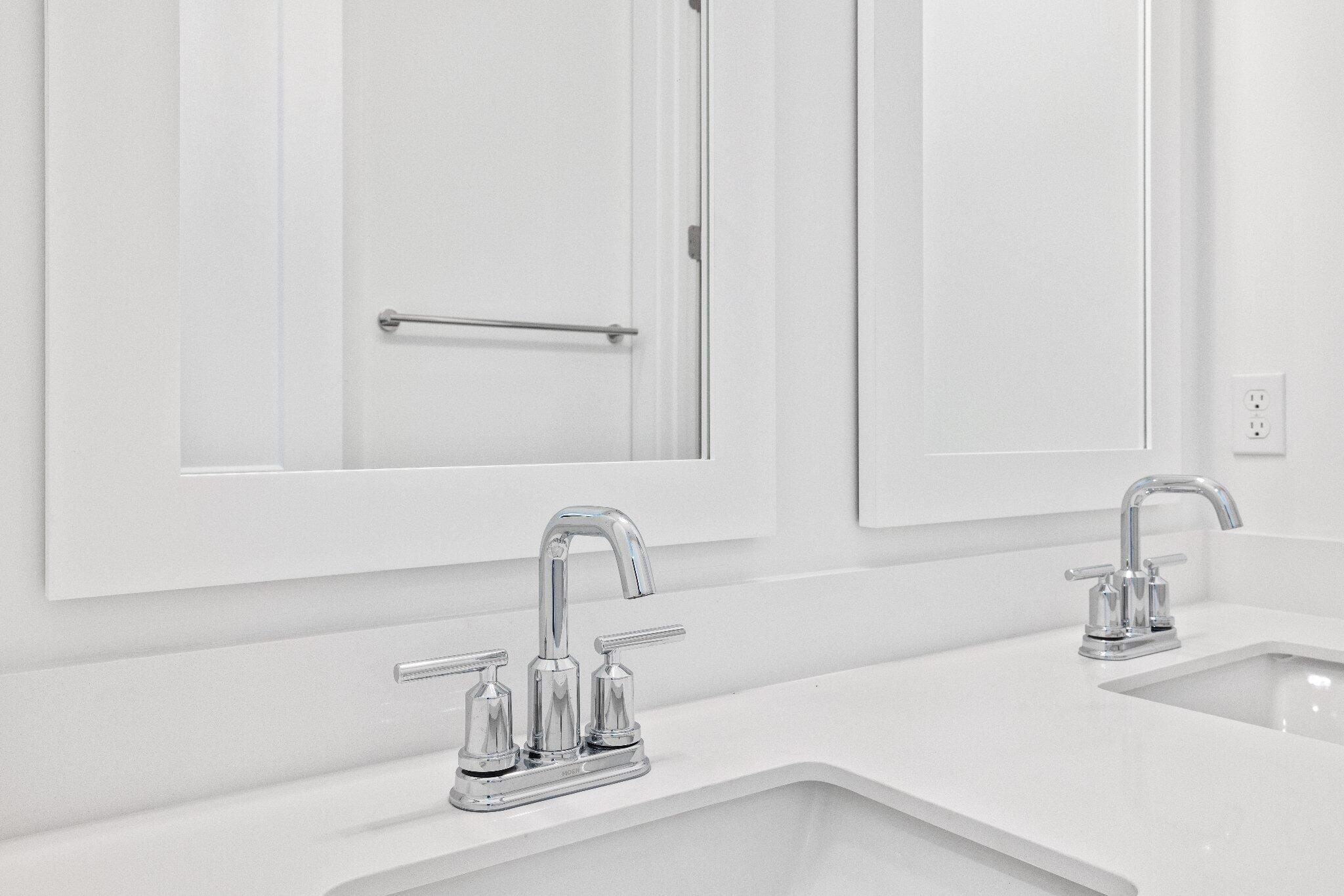 Double vanity featuring white quartz countertops, dual undermount sinks, polished chrome widespread faucets, and matching framed mirrors