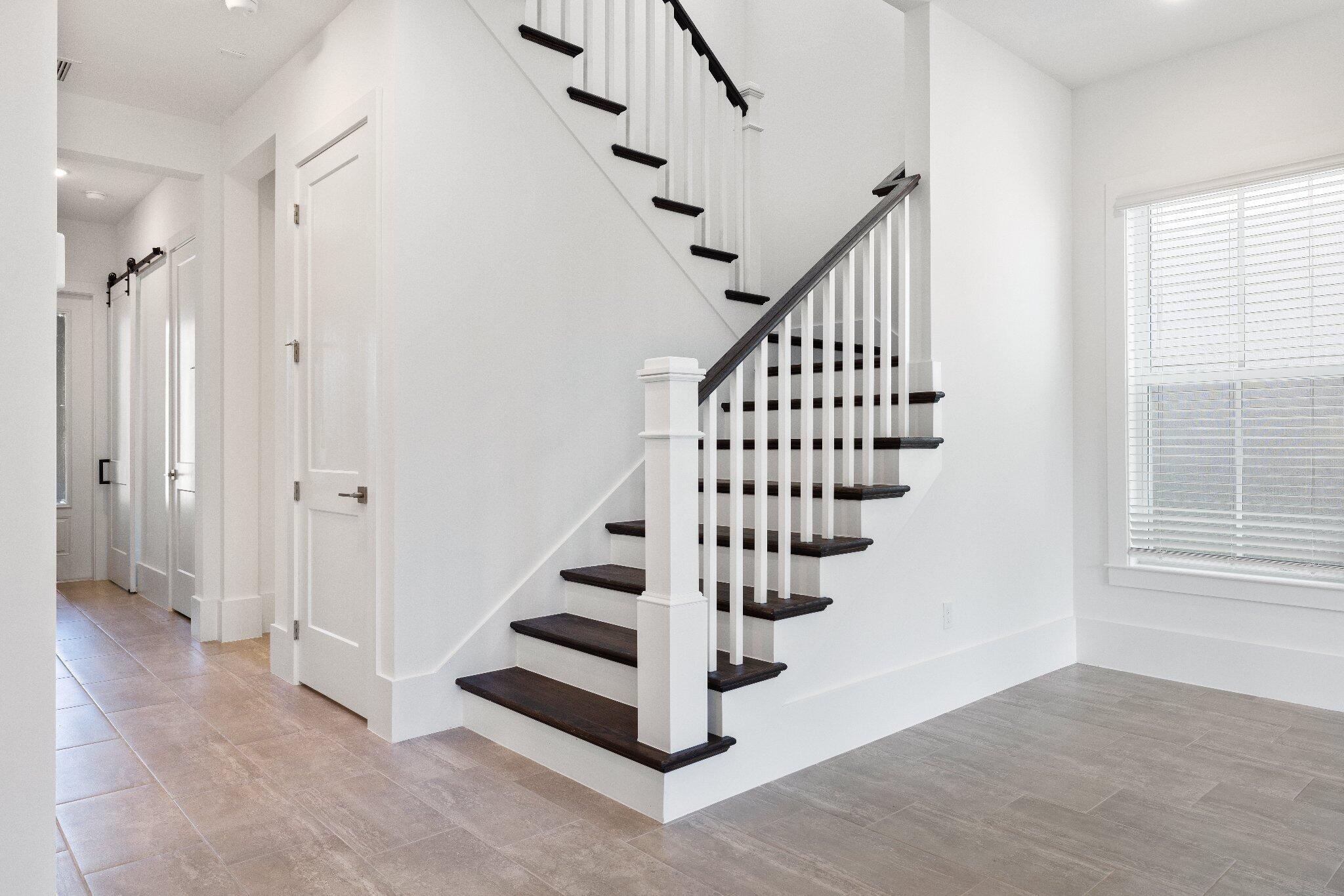 Staircase featuring dark wood-finish treads, white balusters, and a square newel post