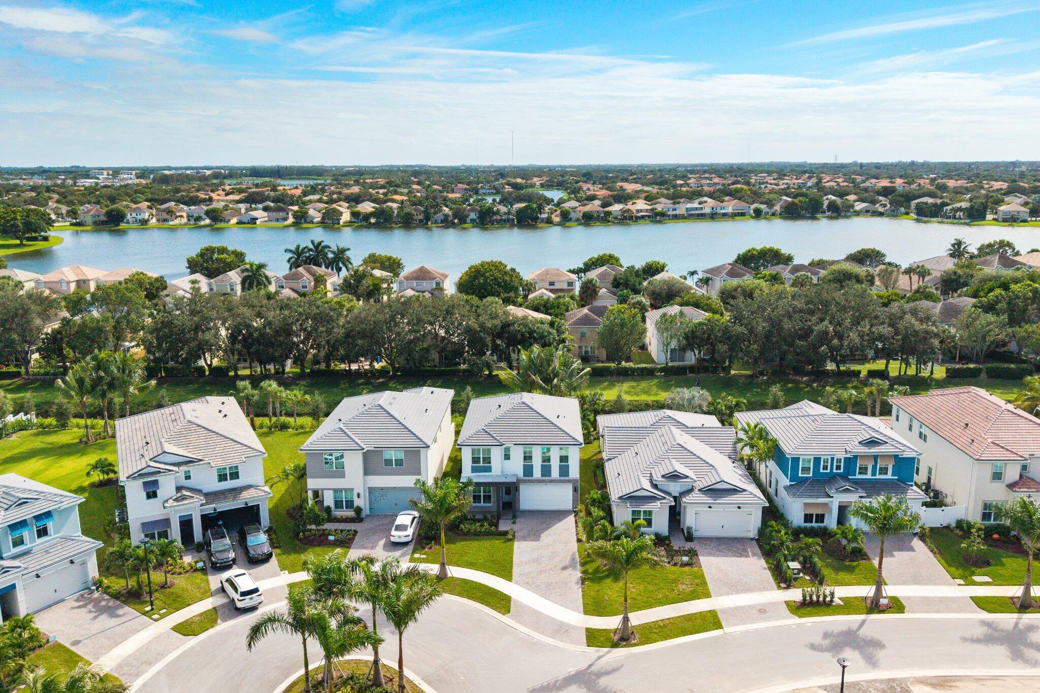 Aerial perspective of a residential neighborhood featuring paved driveways, multi-story single-family residences, tile roofing, and proximity to a large lake