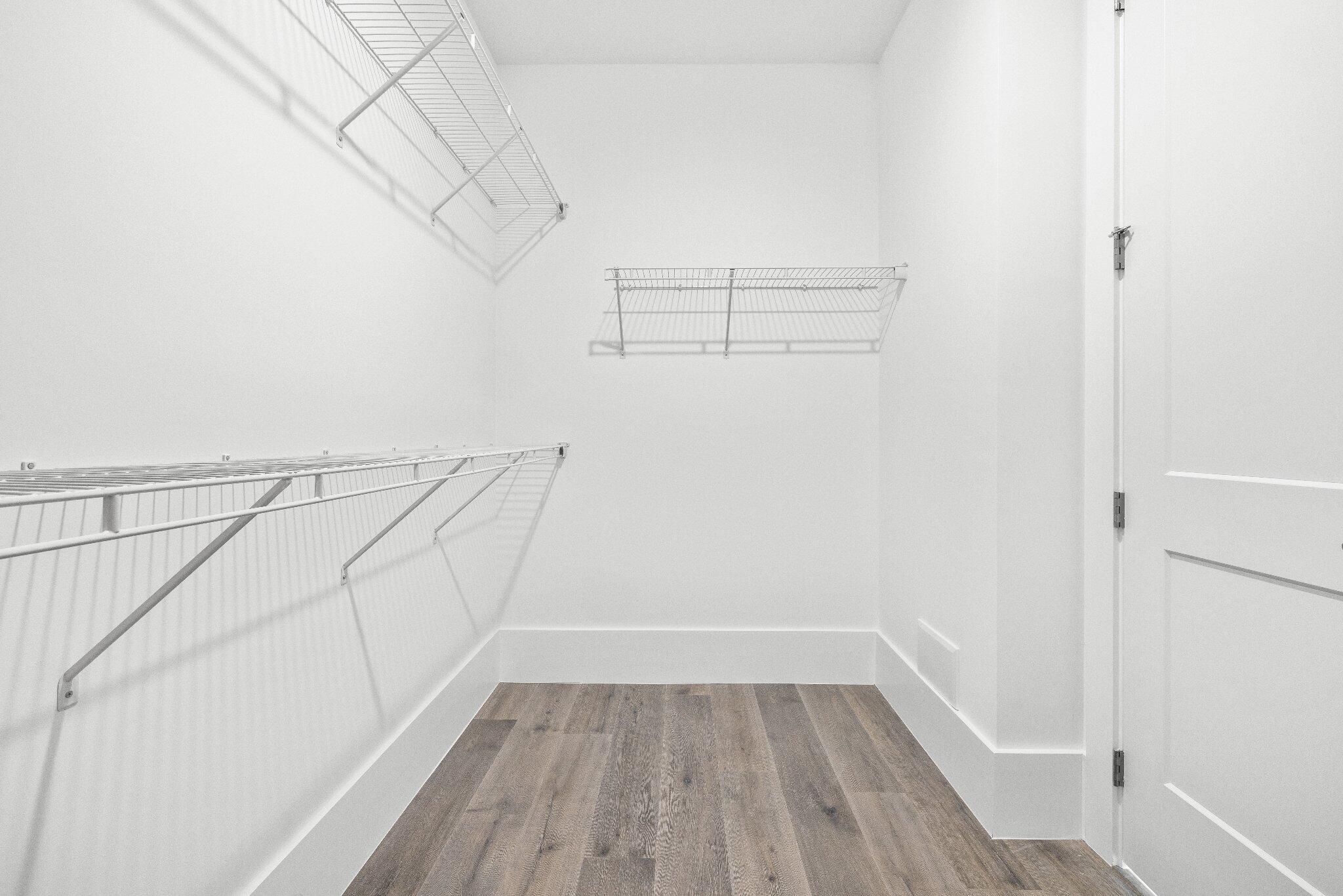 Walk-in storage space featuring wood-finish flooring and multi-level white wire shelving