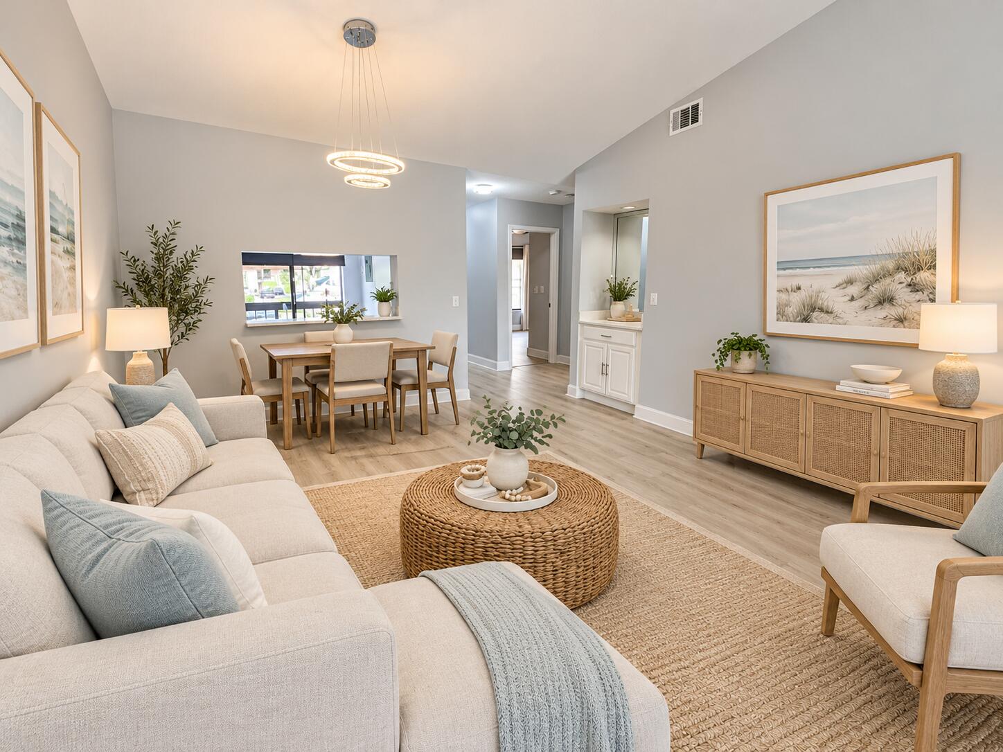 Vaulted ceiling, open-concept floor plan, light-toned wood-finish flooring, modern tiered circular light fixture, and built-in cabinetry with a mirror inlay