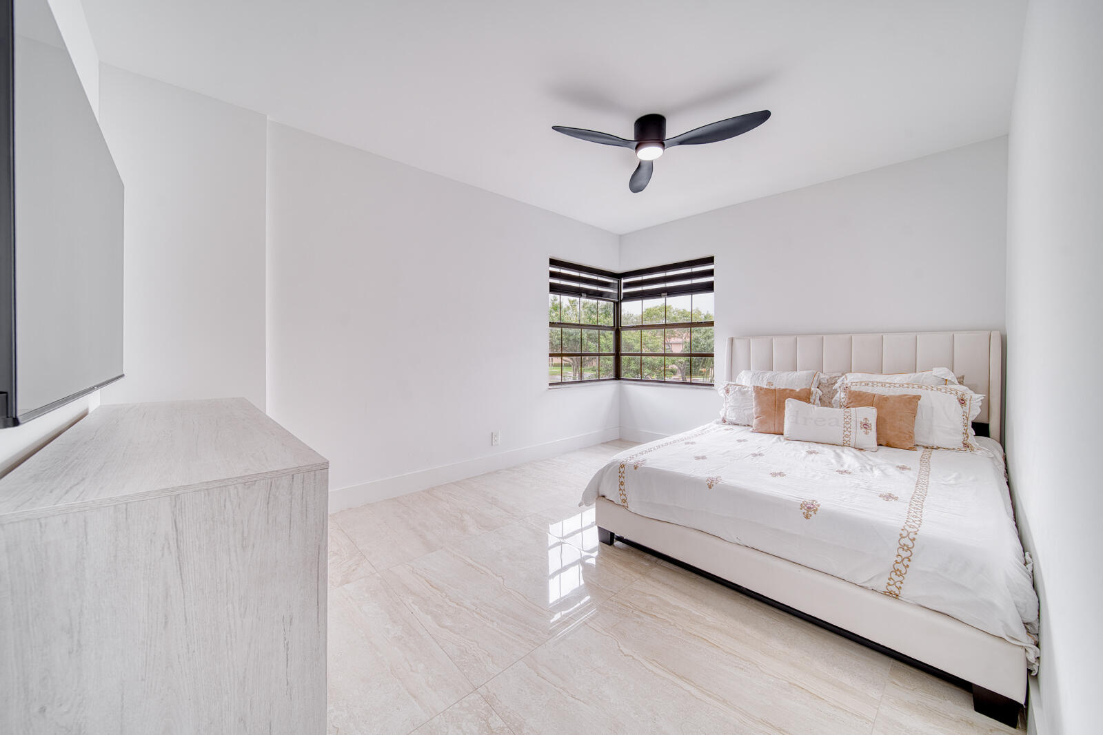 Bright second bedroom with porcelain tile flooring.
