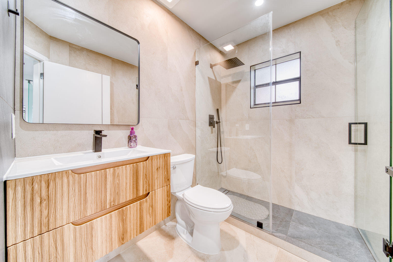 Glass-enclosed shower with floor-to-ceiling tile and floating vanity.