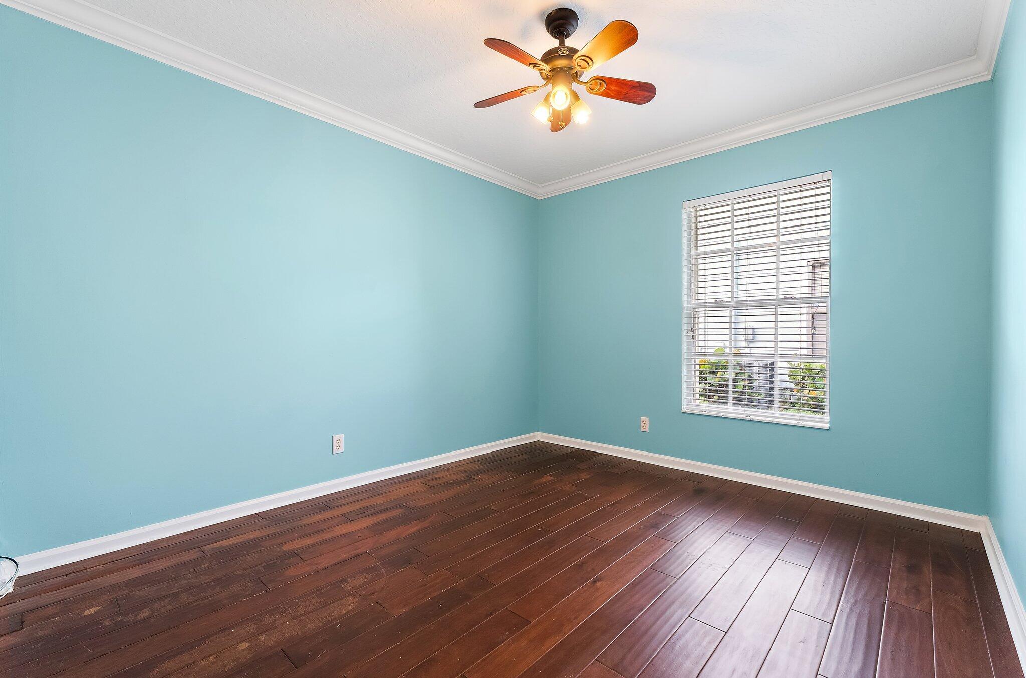 Guest bedroom with wood floors and a ceiling fan.