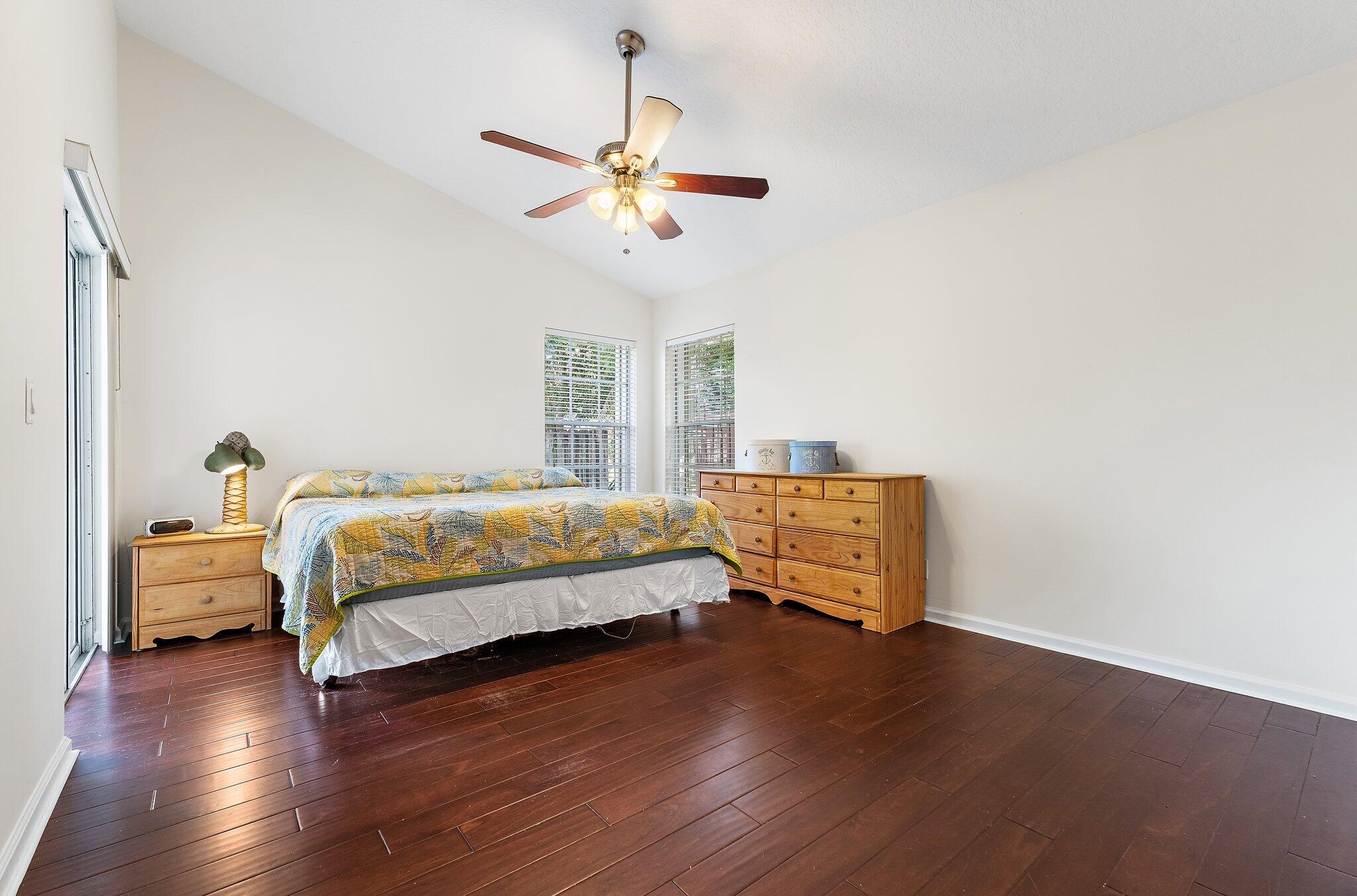 Primary bedroom with wood floors and a ceiling fan.