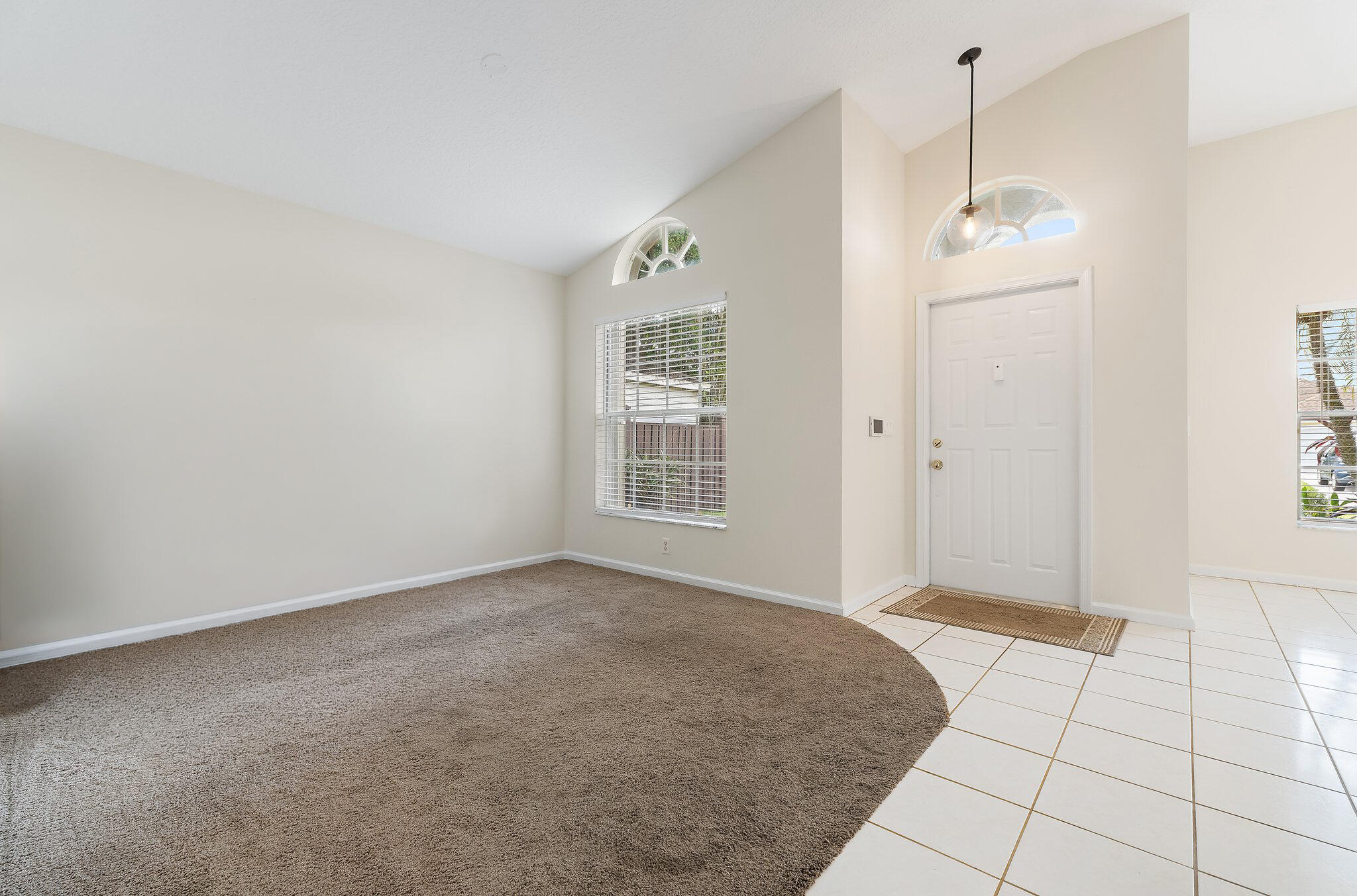 Living room off the front entry, with high ceilings and an arched window.