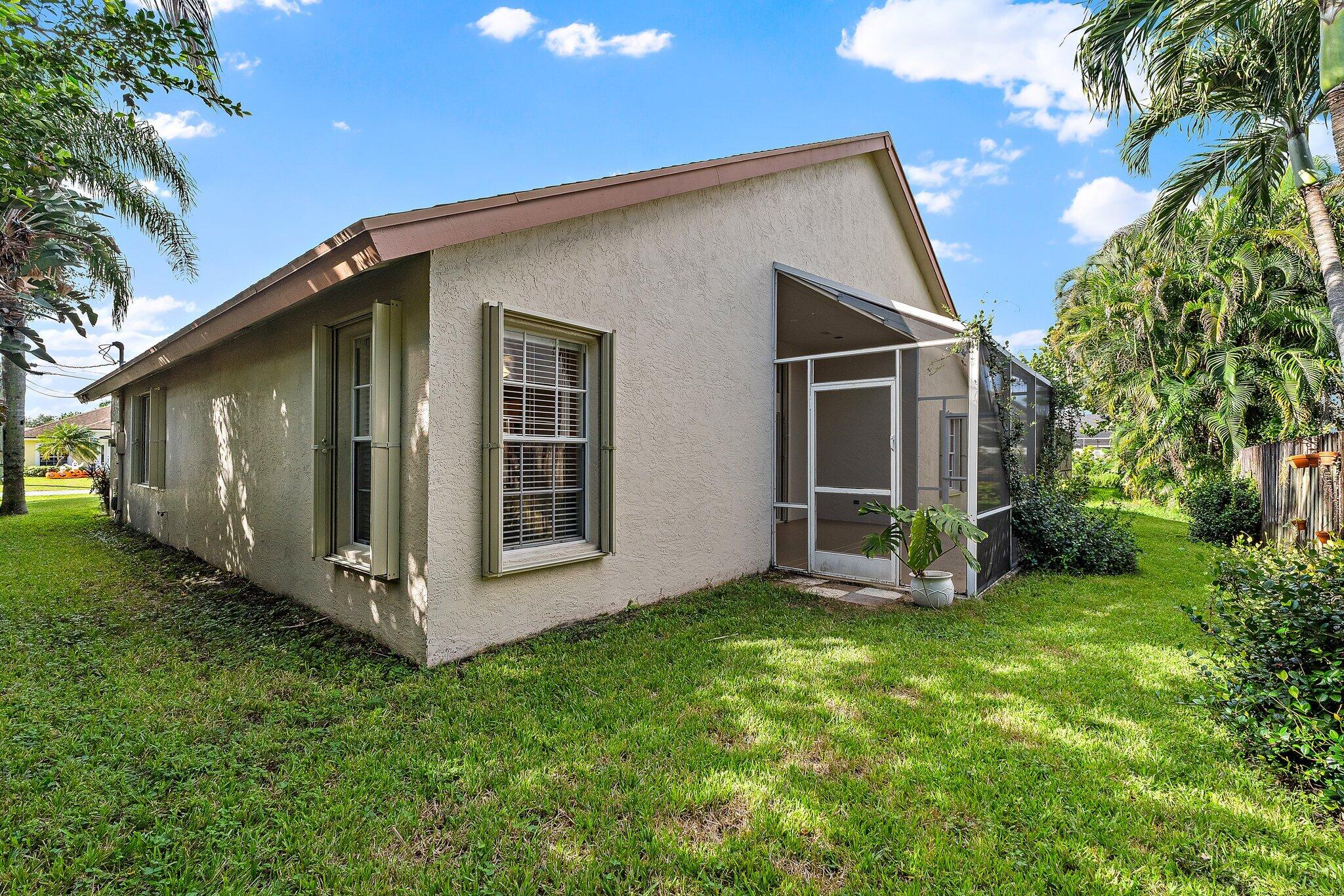 Side of the home and backyard with mature palms.