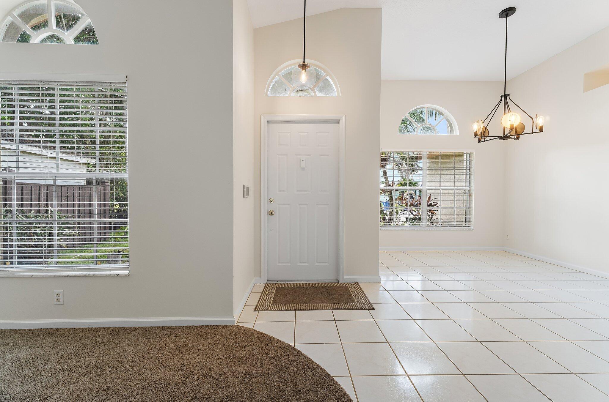 Foyer with tile floors, a chandelier and an arched window.
