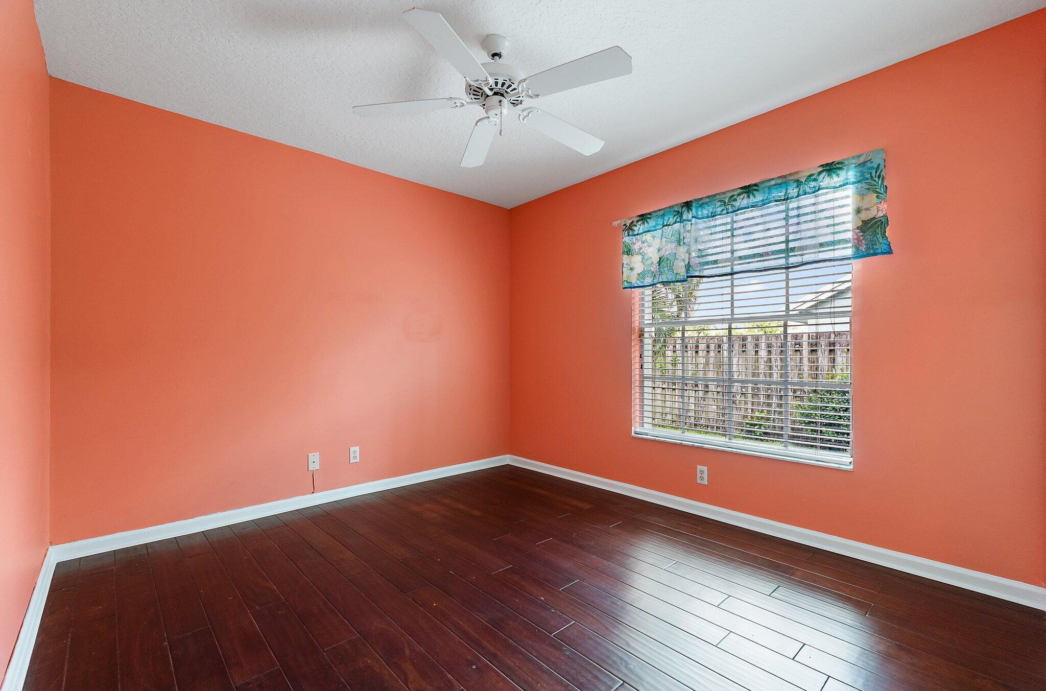 Guest bedroom with wood floors and a ceiling fan.