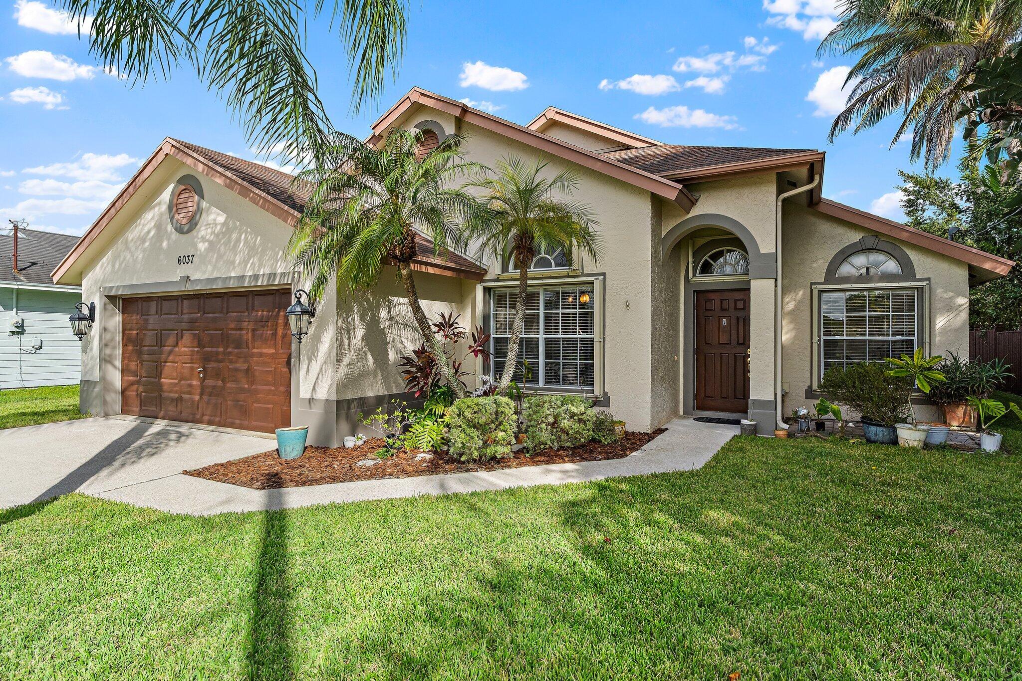 Single-story CBS home with tropical landscaping and an attached 2-car garage.