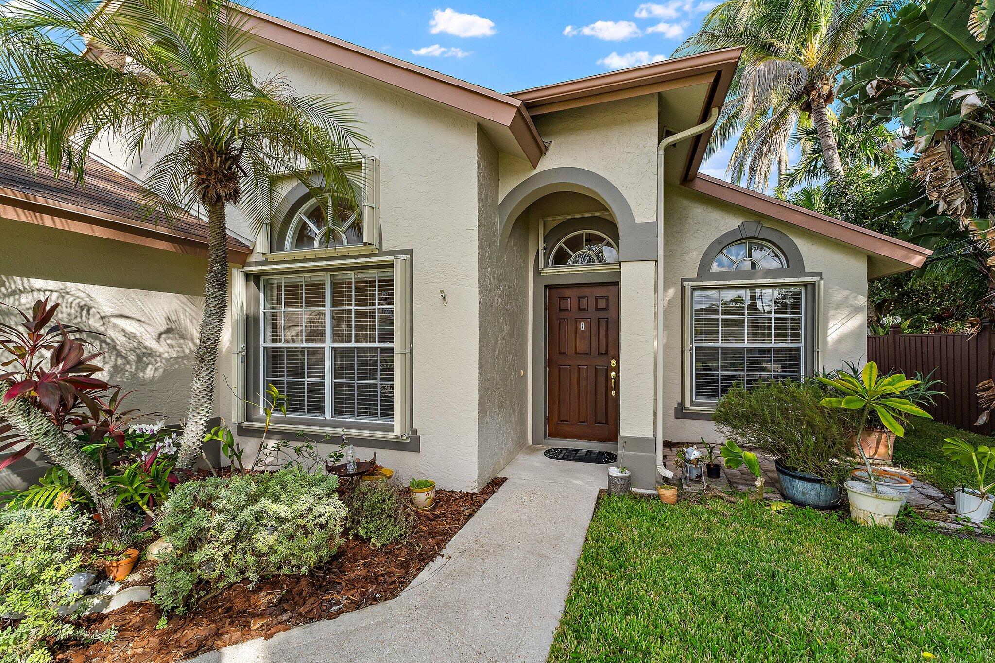 Front entry with arched windows and tropical landscaping.