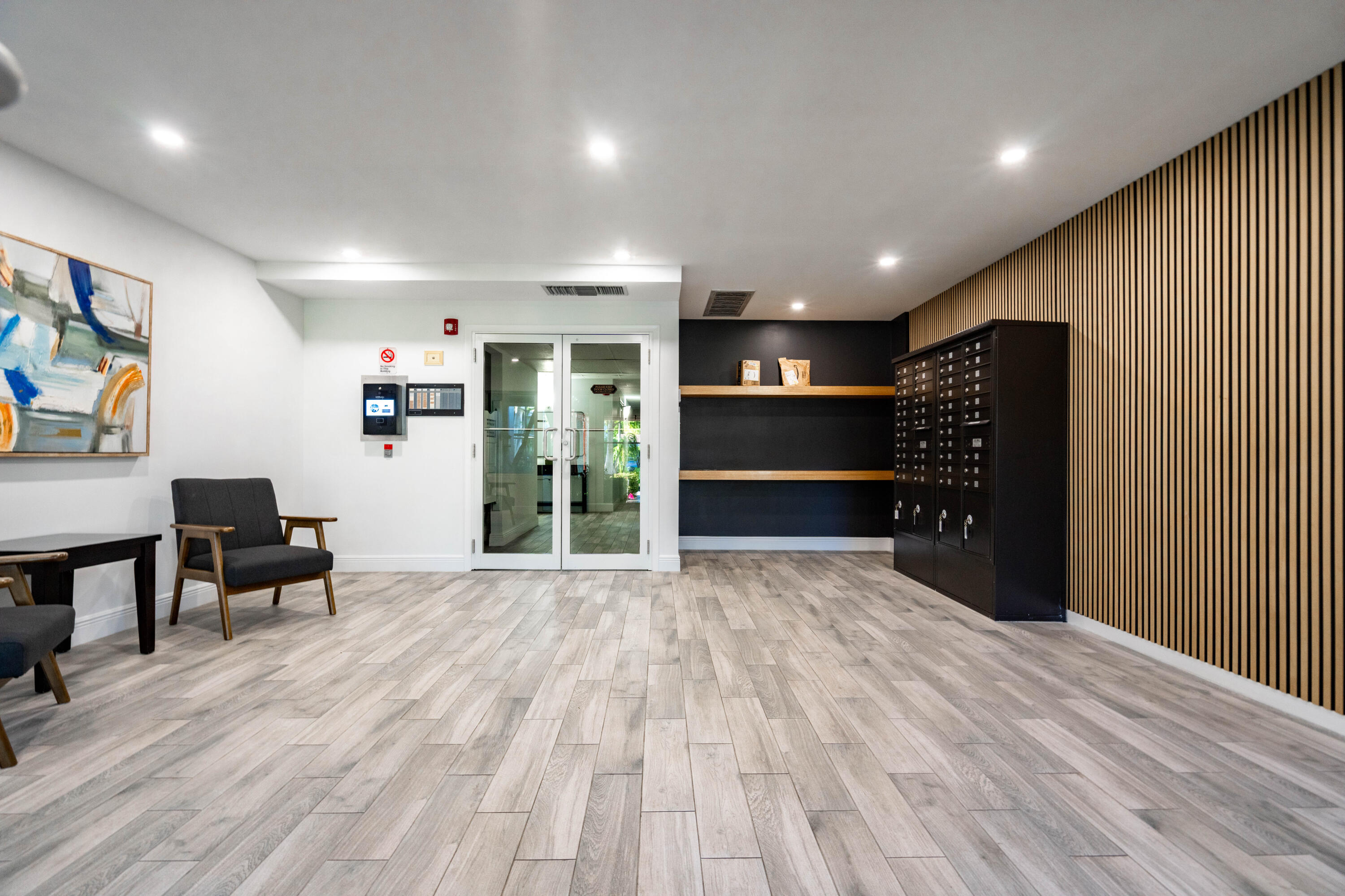 Lobby featuring wood-slat accent wall, tile flooring with wood finish, recessed lighting, built-in wall-mounted shelving, and integrated mailboxes