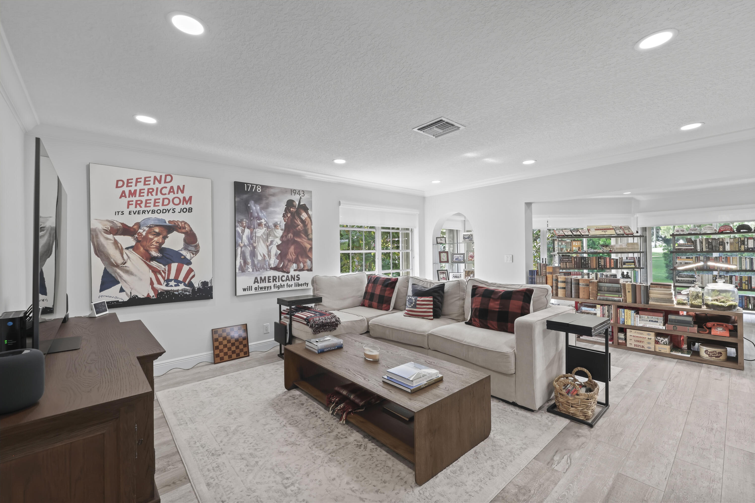 Open-concept living space featuring wood-finish flooring, recessed lighting, multi-pane windows, and an arched architectural opening