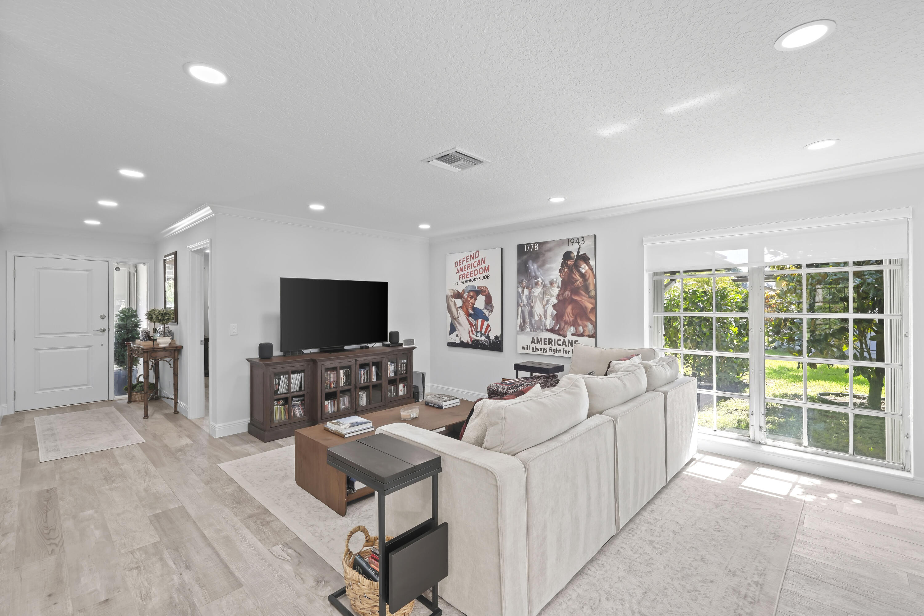Open-concept interior featuring light wood-finish flooring, recessed lighting, and large grid-pattern windows