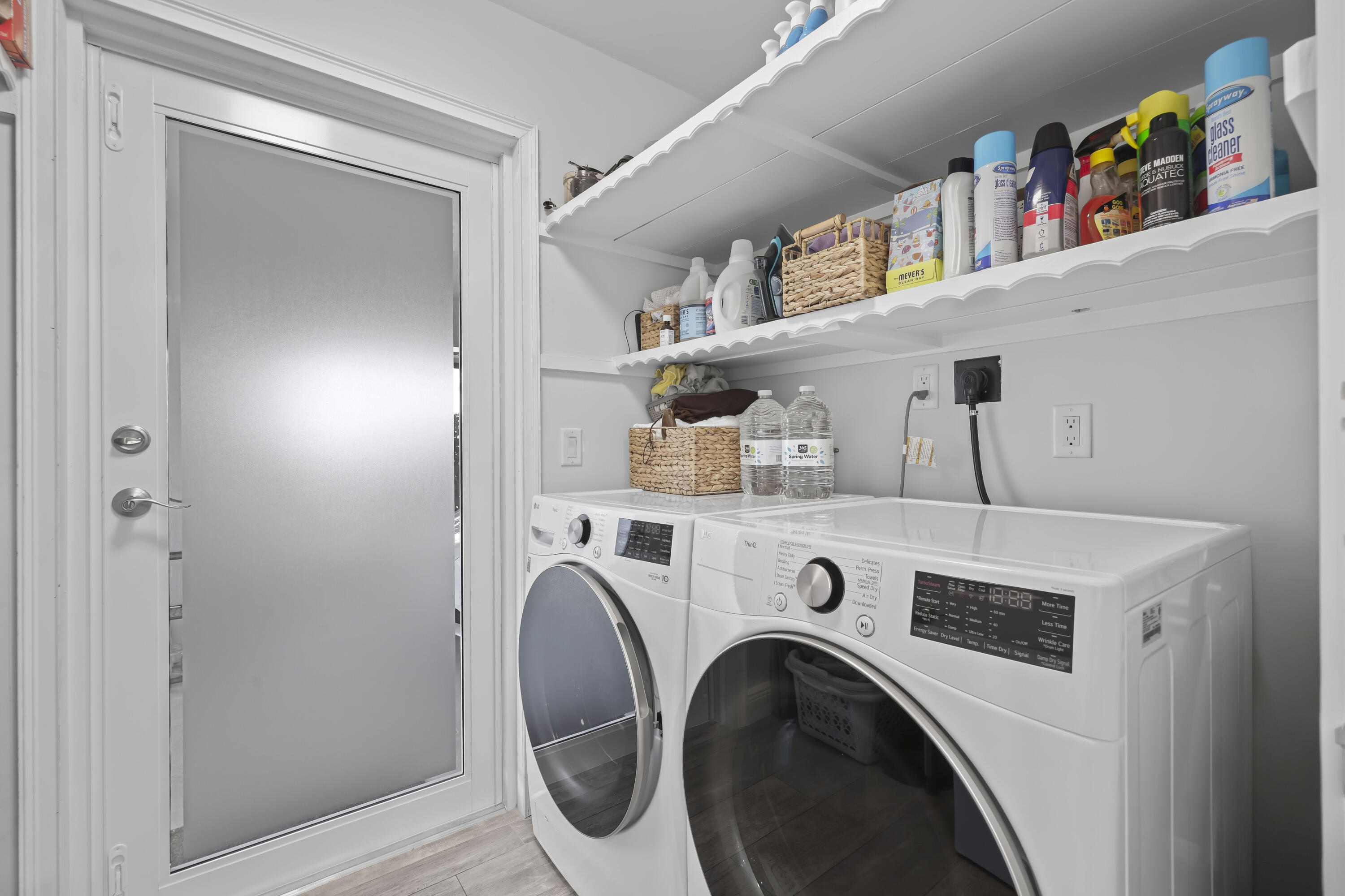 Laundry room featuring dual scalloped-edge wood shelves, an exterior door with frosted glass inlay, and white cabinetry finish