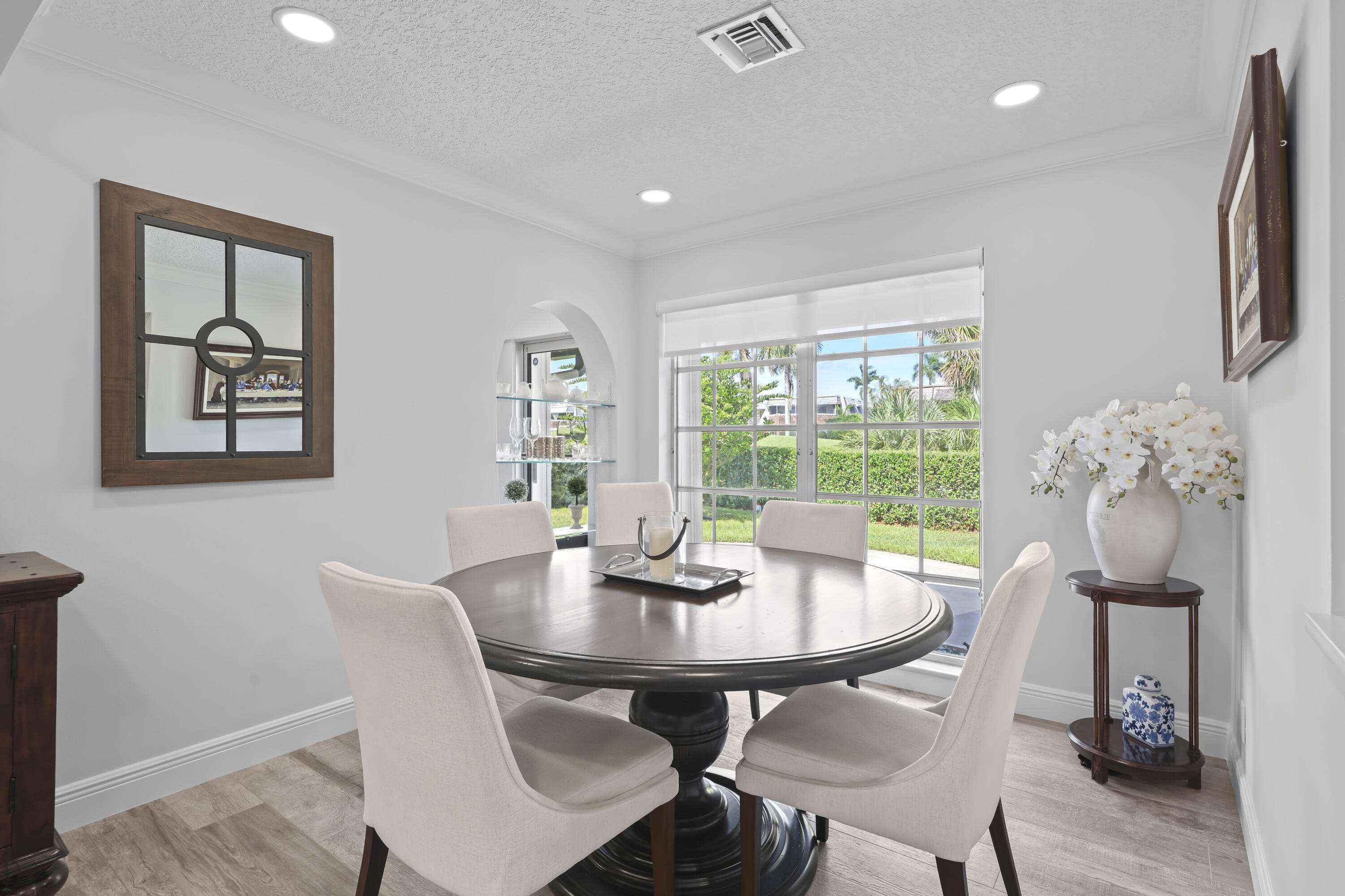Dining area featuring wood-finish flooring, recessed lighting, a wide window with exterior landscape exposure, and a built-in arched display niche with glass shelving