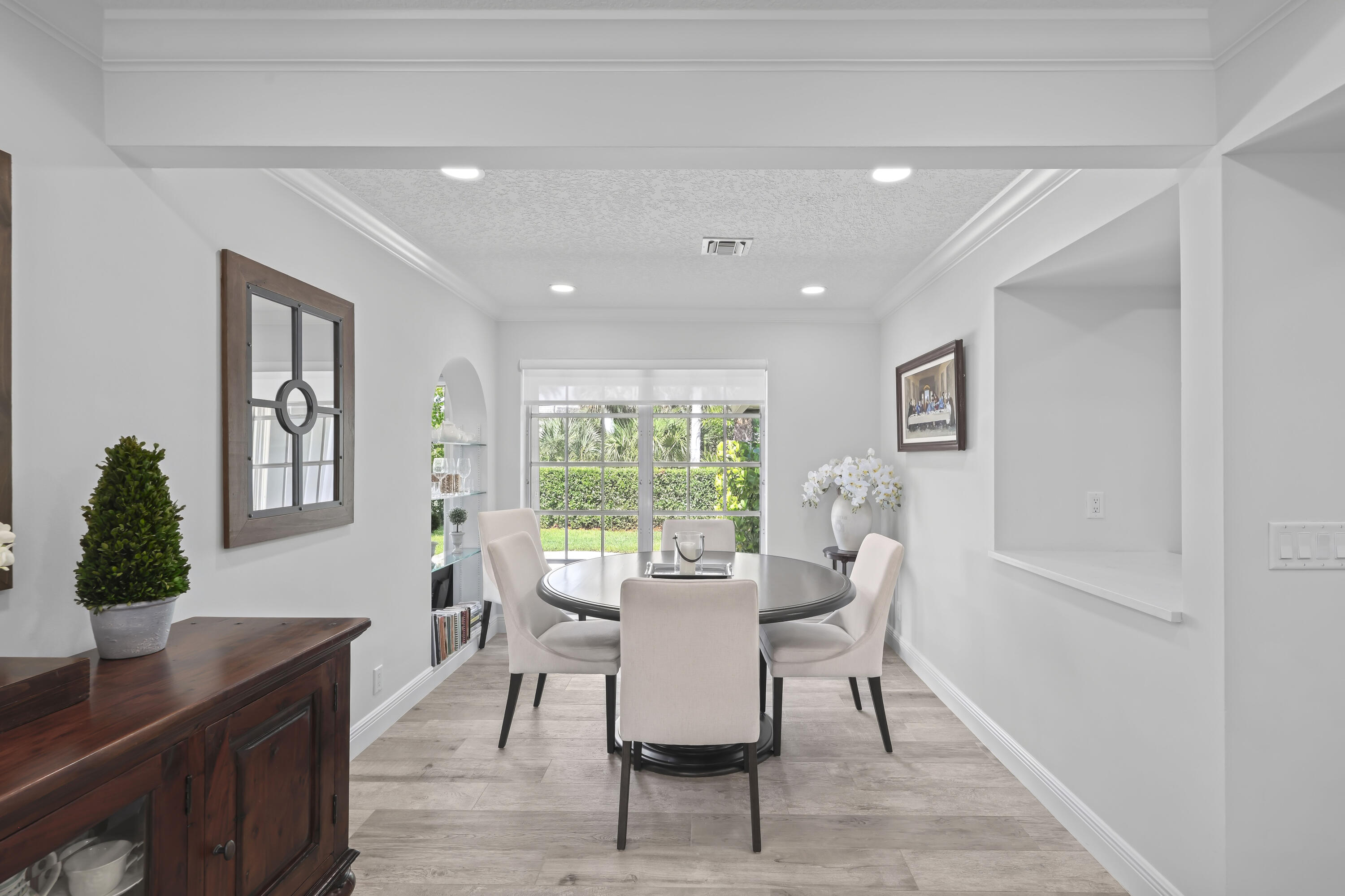 Interior space featuring wood-finish flooring, recessed lighting, crown molding, a built-in arched display niche, and a pass-through opening