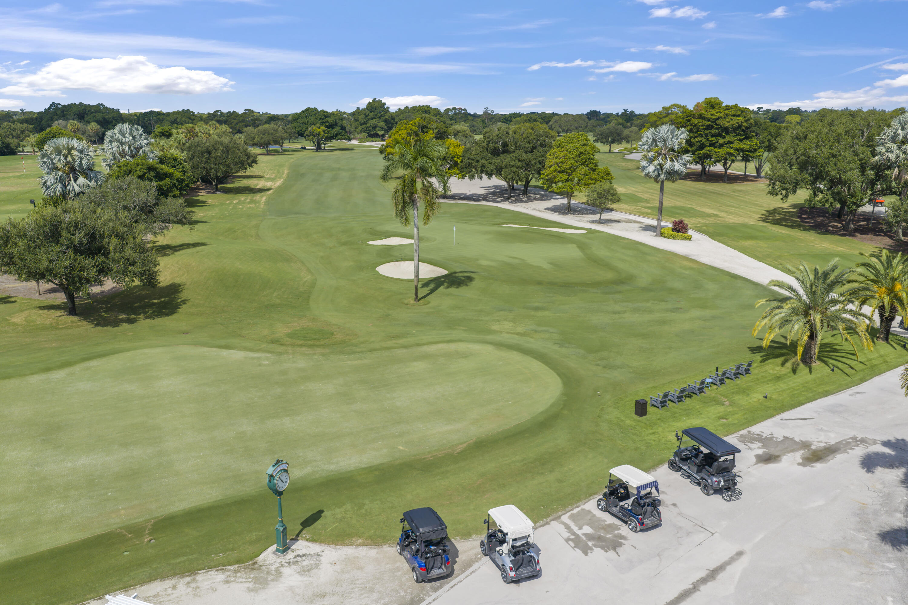 Expansive golf course grounds featuring manicured fairways, sand bunkers, mature trees, and palm landscaping