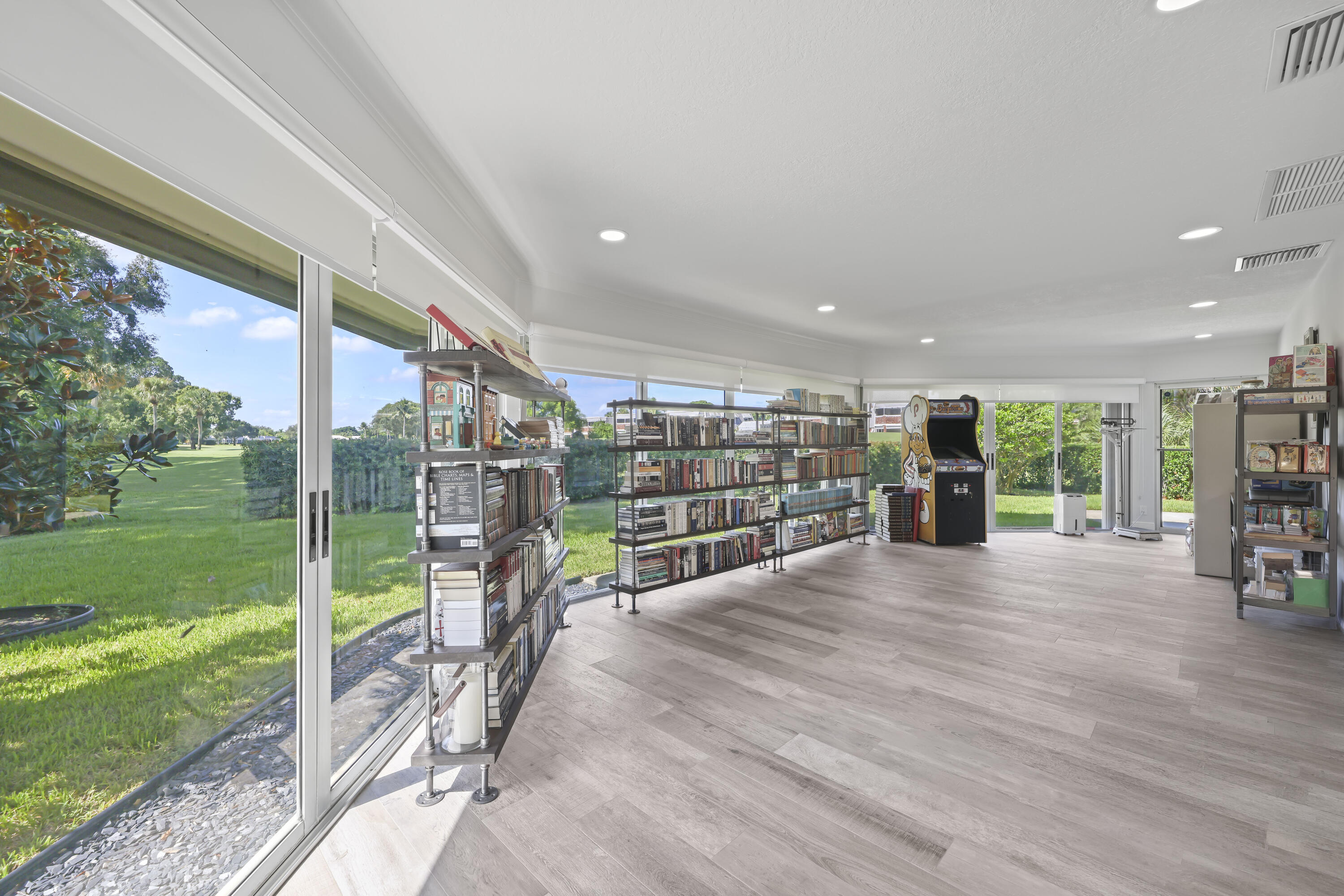 Expansive interior space featuring wood-finish flooring, recessed lighting, and wrap-around sliding glass doors providing exposure to the exterior grounds