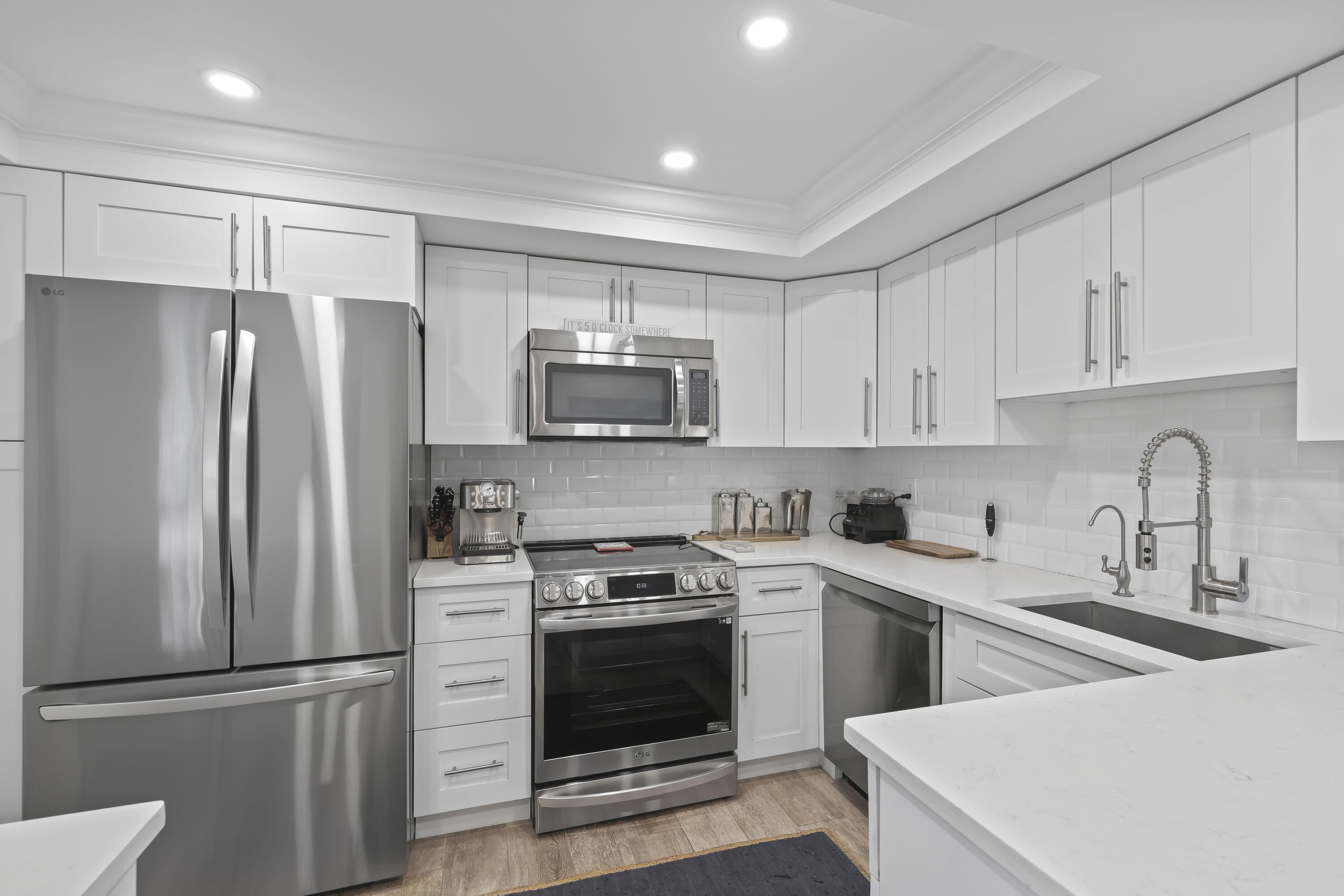 Kitchen featuring white Shaker-style cabinetry, white countertops, a subway tile backsplash, stainless steel appliances, and a gooseneck faucet