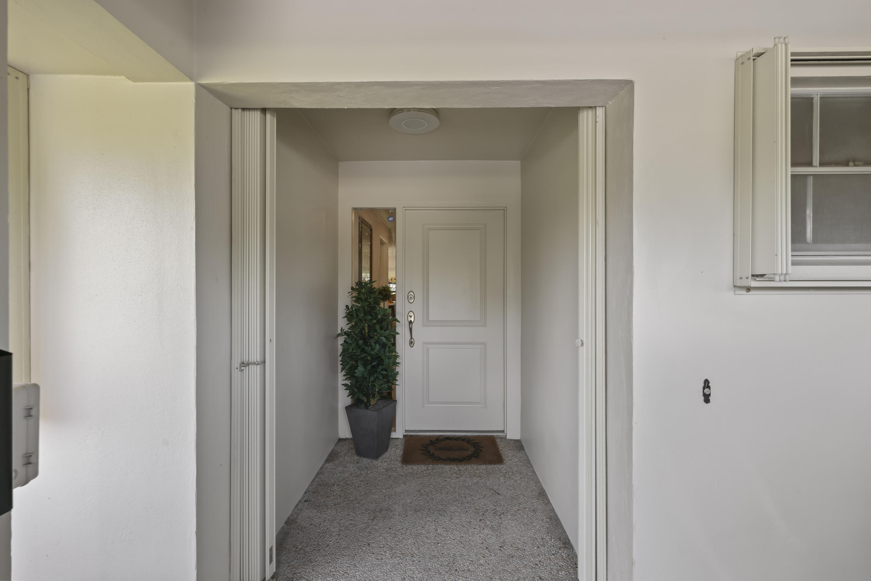 Covered entry featuring a paneled door, sidelight, flush-mount ceiling light, and textured concrete flooring