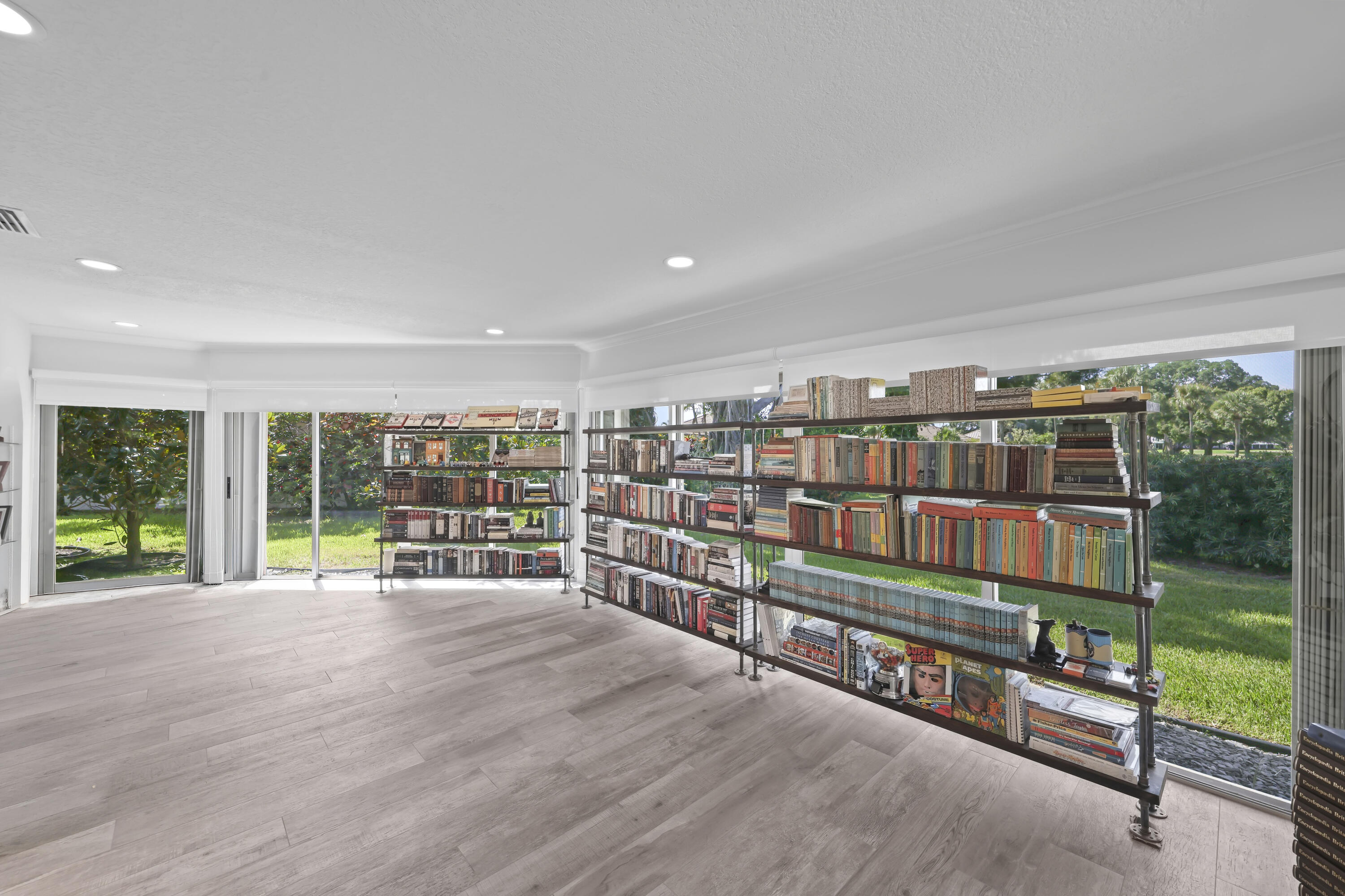 Light-filled room featuring wood-finish flooring, recessed lighting, and extensive floor-to-ceiling glass wall panels