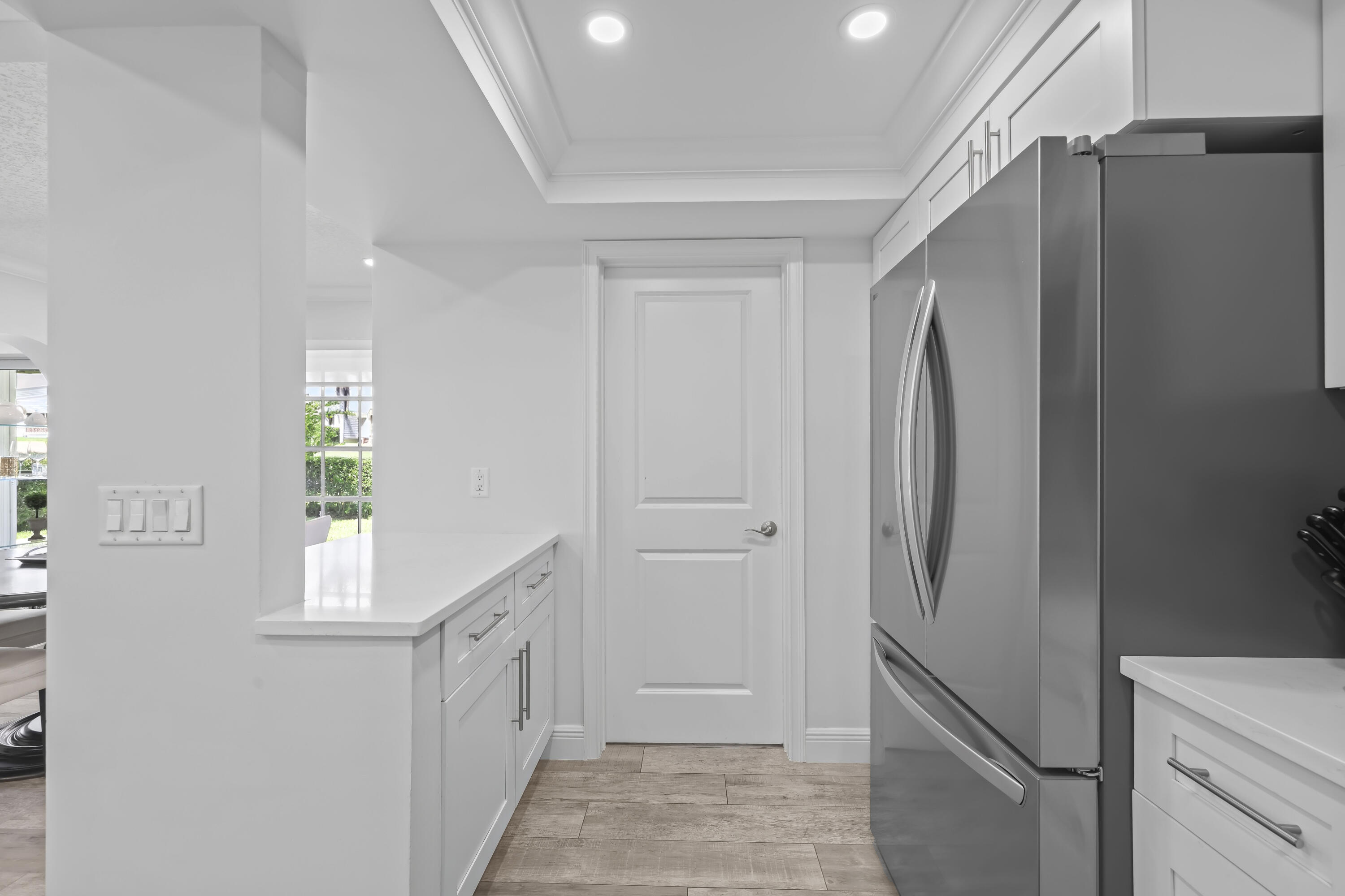 Kitchen featuring white cabinetry, quartz countertops, recessed ceiling lighting, stainless steel refrigerator, and wood-finish flooring