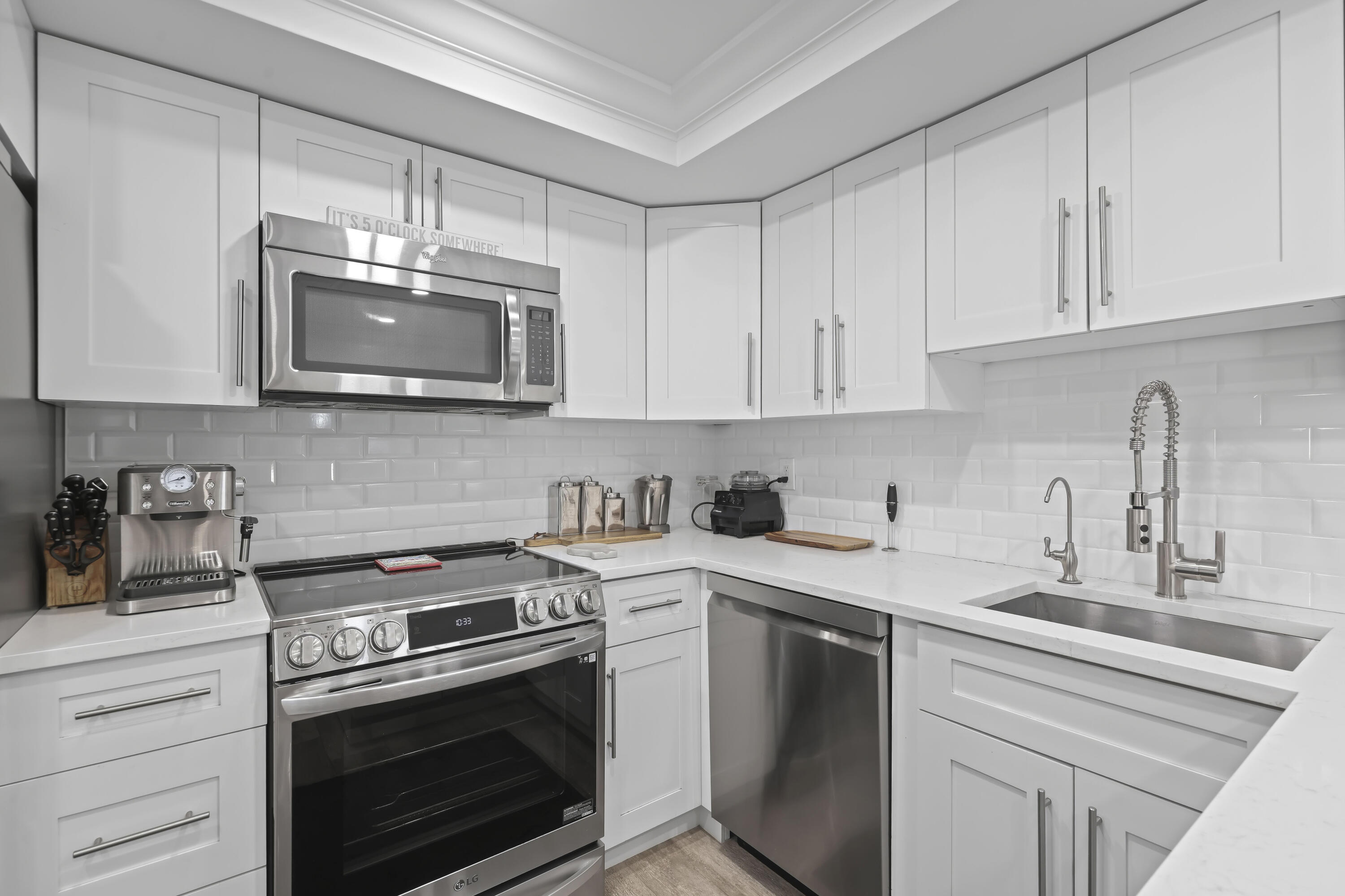 Kitchen featuring white shaker-style cabinetry, quartz countertops, white subway tile backsplash, stainless steel appliances, and a gooseneck faucet