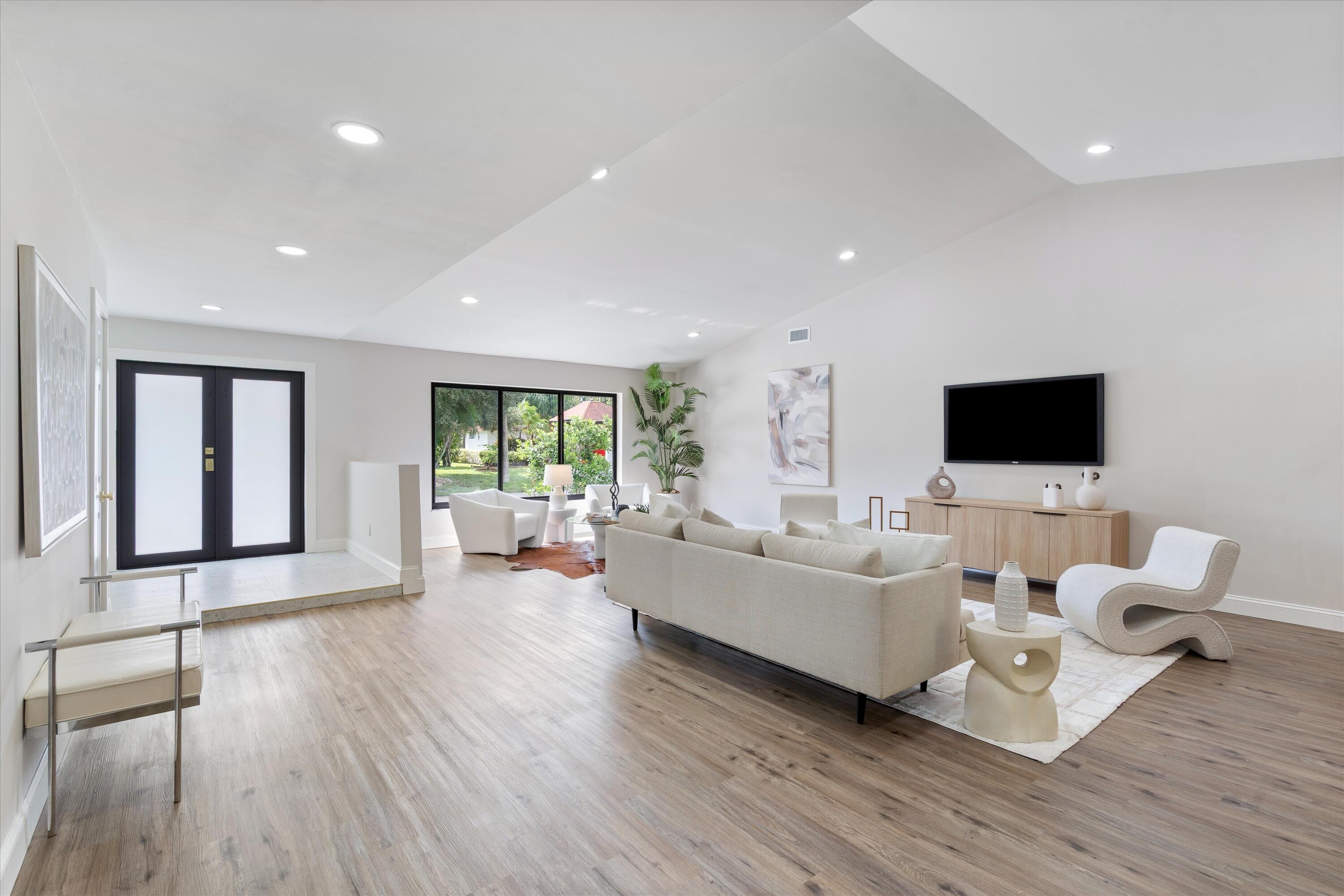 Vaulted ceilings, wood-finish flooring, recessed lighting, and black-framed windows featuring double entry doors Vaulted ceilings, wood-finish flooring, recessed lighting, and black-framed windows featuring double entry doors