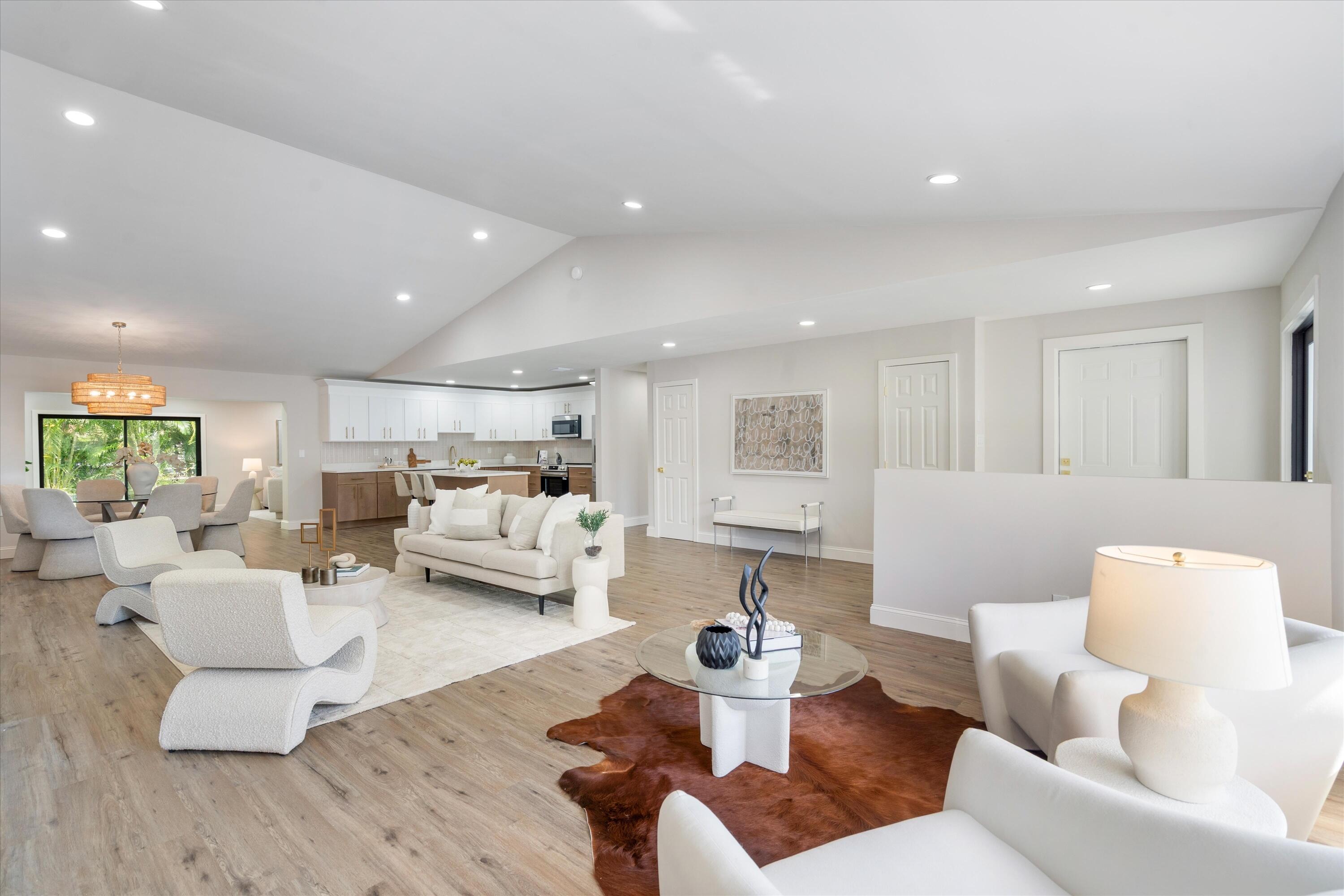 Vaulted ceilings, wood-finish flooring, recessed lighting, and white kitchen cabinetry Vaulted ceilings, wood-finish flooring, recessed lighting, and white kitchen cabinetry