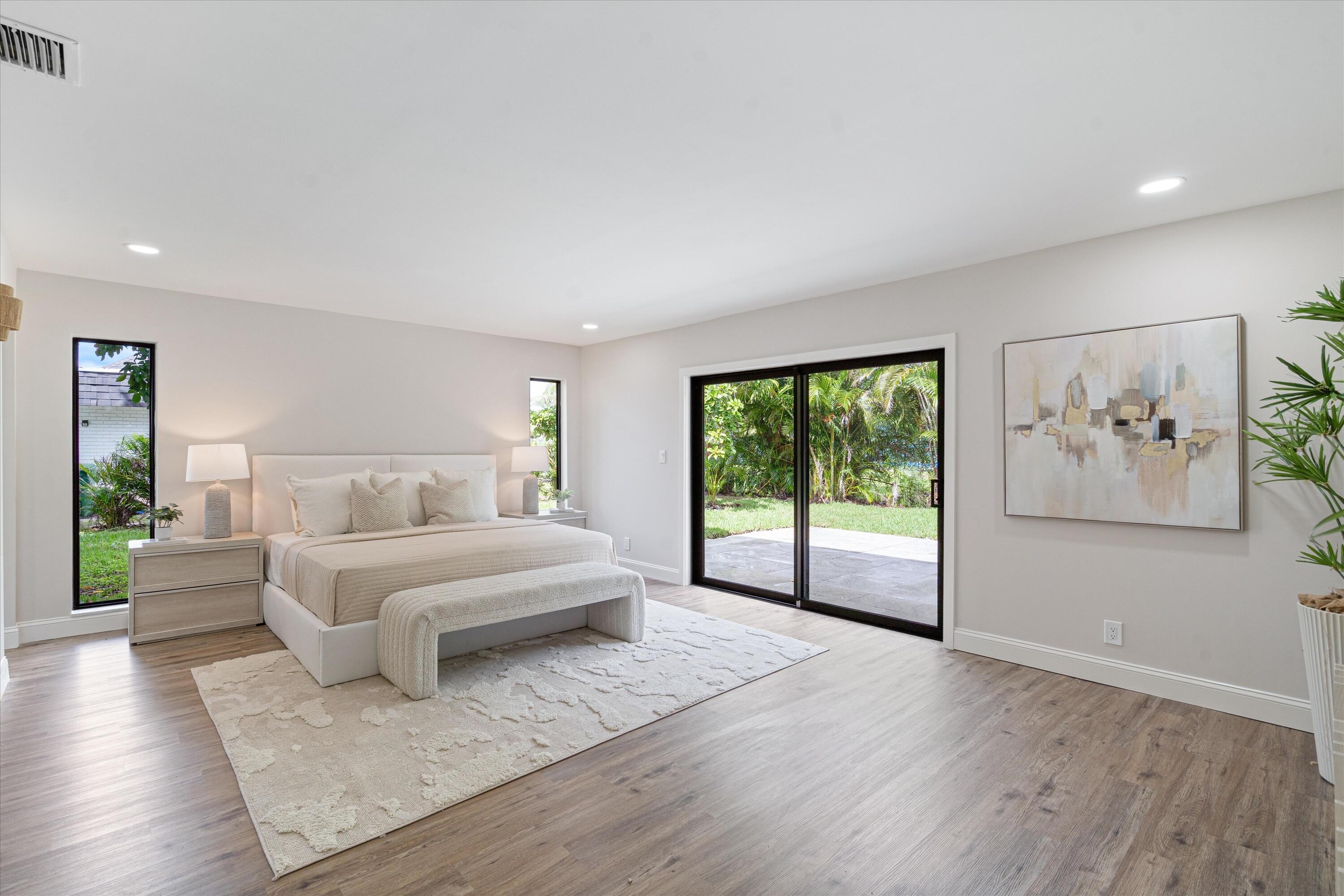Spacious room with wood-finish flooring, recessed lighting, vertical windows, and black-framed sliding glass doors opening to the exterior