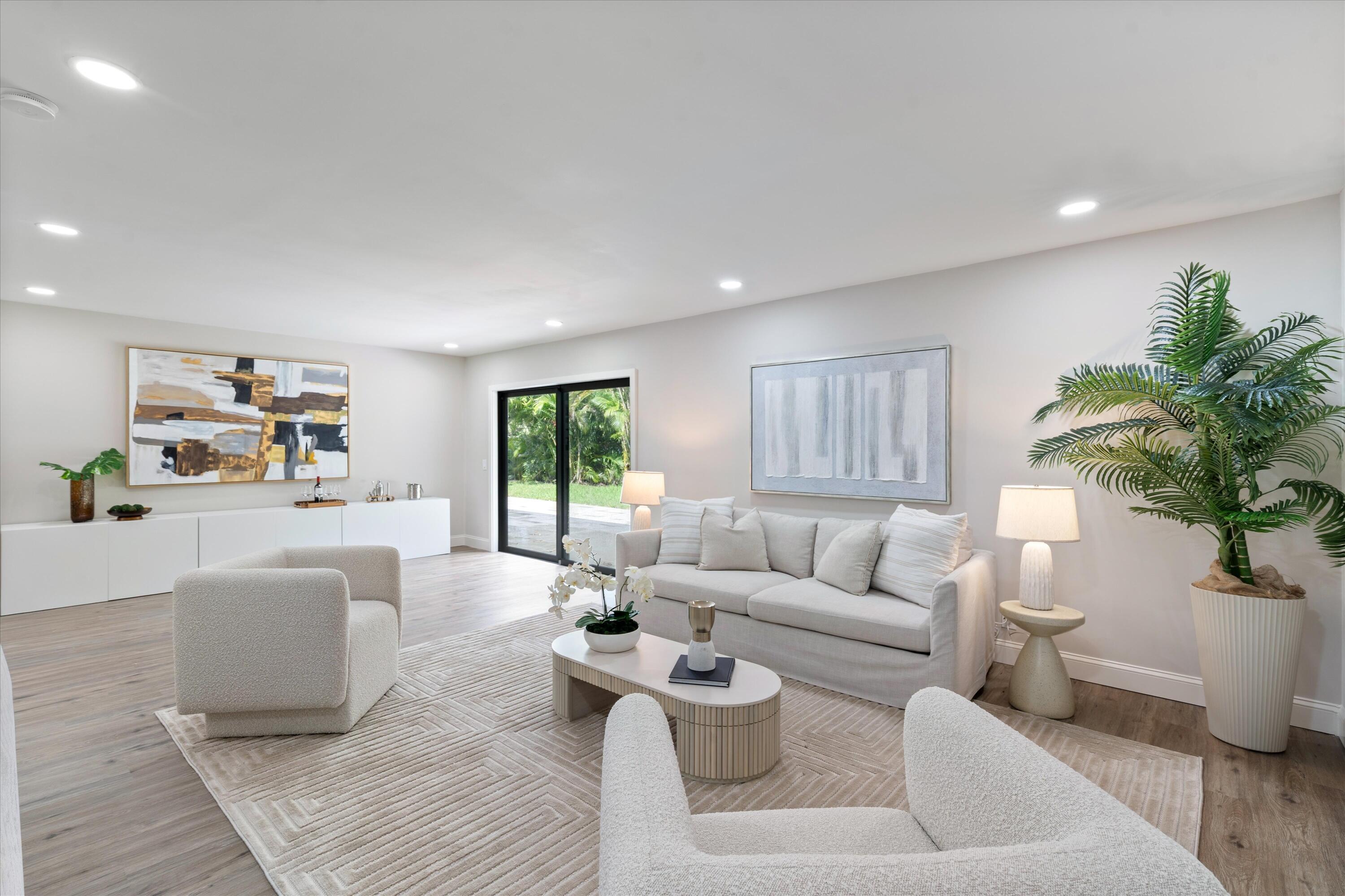 Open-concept interior featuring wood-finish flooring, recessed lighting, and black-framed sliding glass doors Open-concept interior featuring wood-finish flooring, recessed lighting, and black-framed sliding glass doors