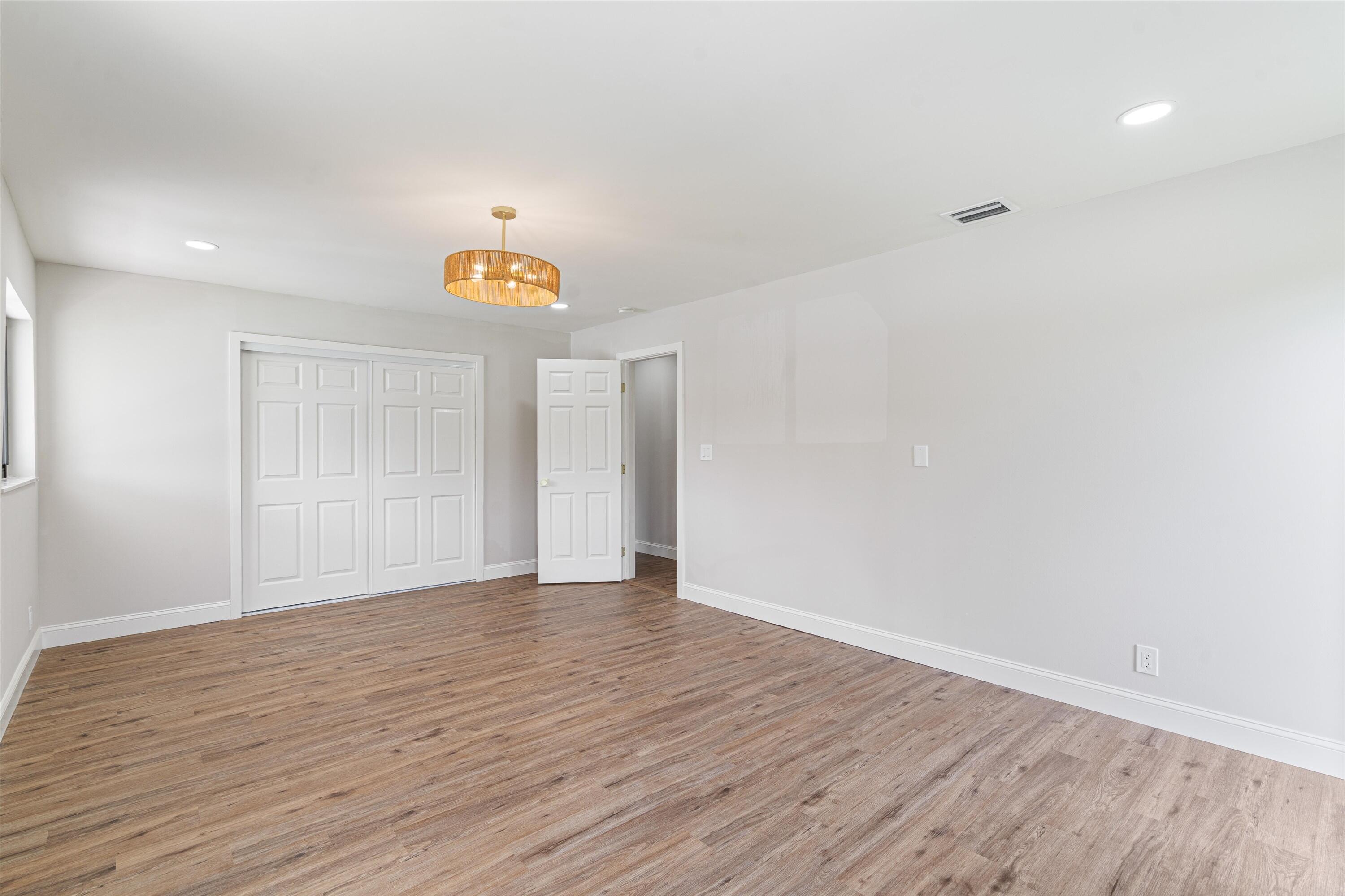 Interior space featuring wood-finish flooring, recessed lighting, a drum-style chandelier, and paneled closet doors