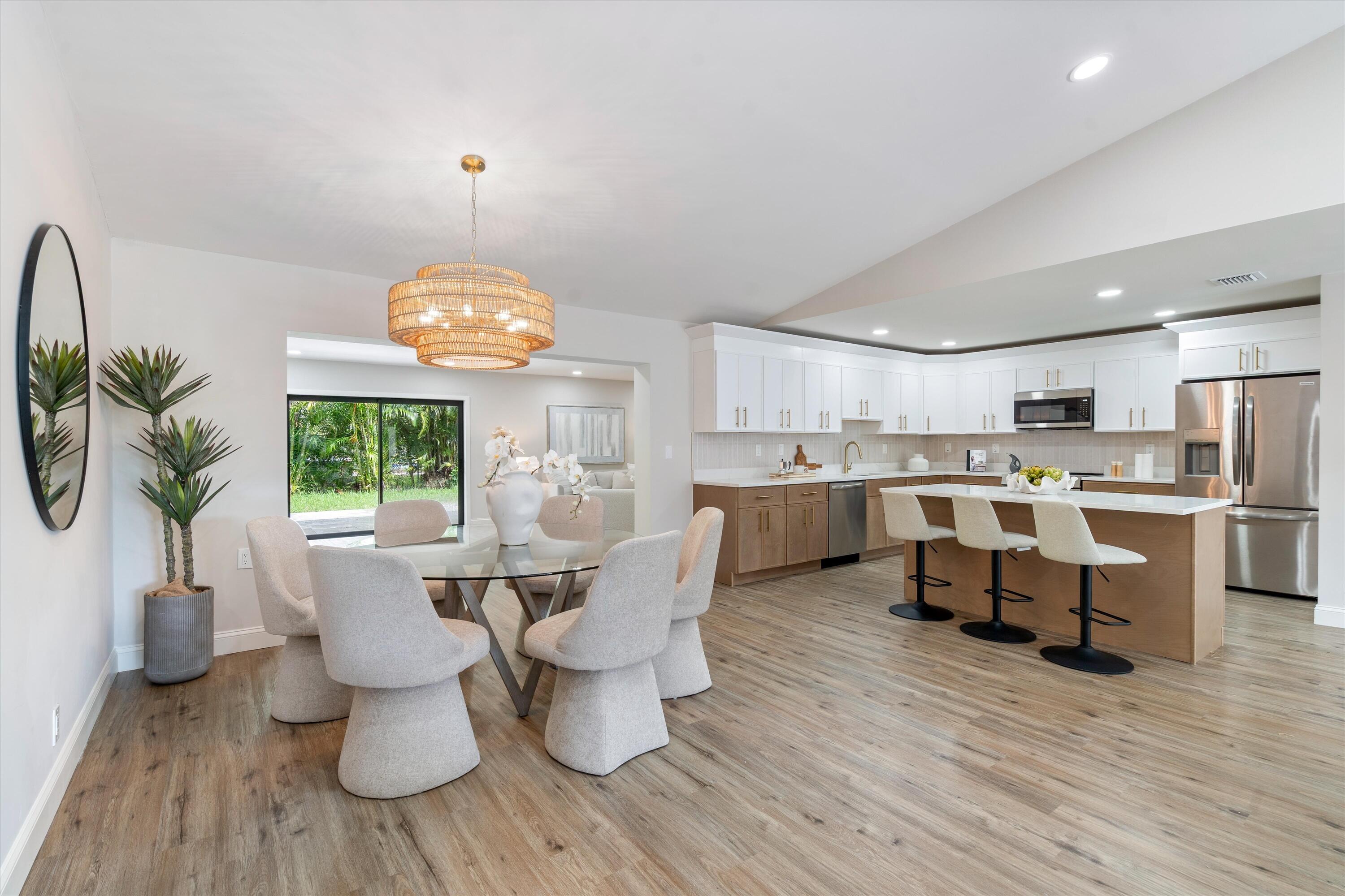 Kitchen featuring wood-finish cabinetry, white upper cabinets, stainless steel appliances, and a central island with a quartz countertop, complemented by wood-finish flooring and a vaulted ceiling Kitchen featuring wood-finish cabinetry, white upper cabinets, stainless steel appliances, and a central island with a quartz countertop, complemented by wood-finish flooring and a vaulted ceiling