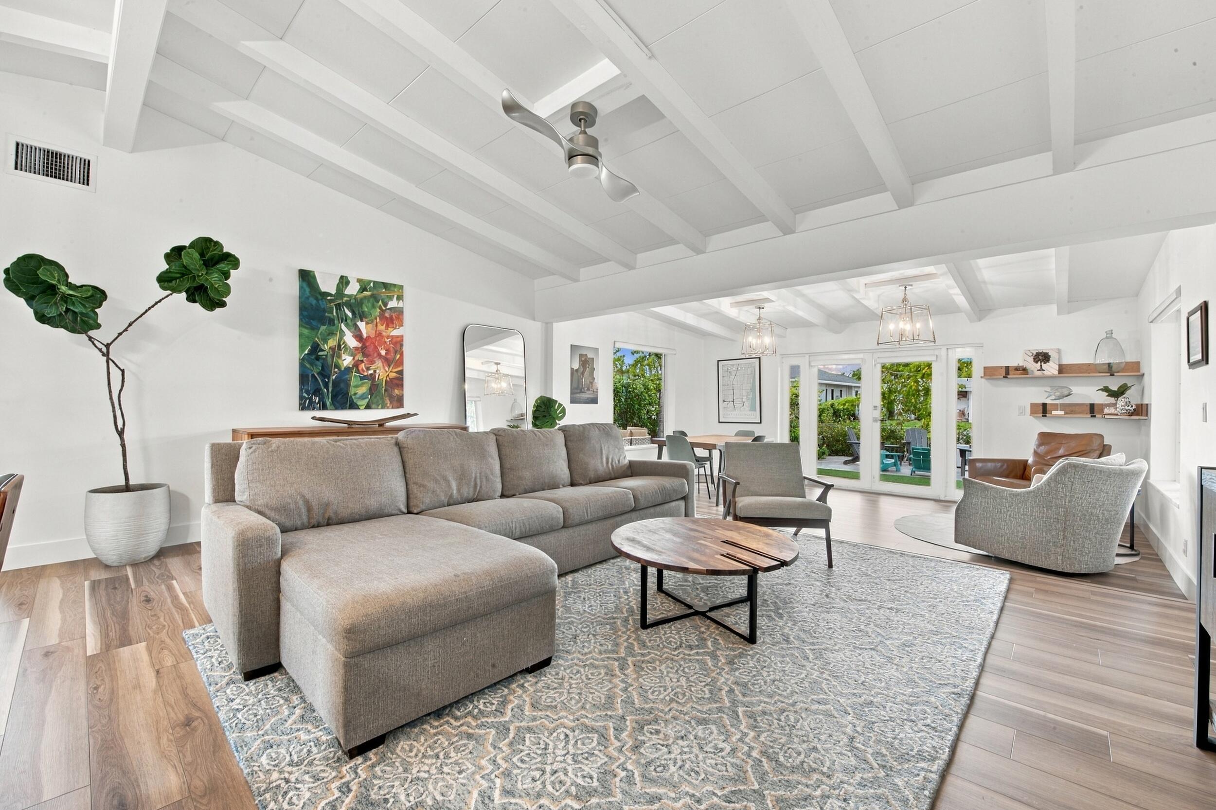 Vaulted ceiling with exposed beams, wood-finish flooring, ceiling fan, and double glass-paneled exterior doors