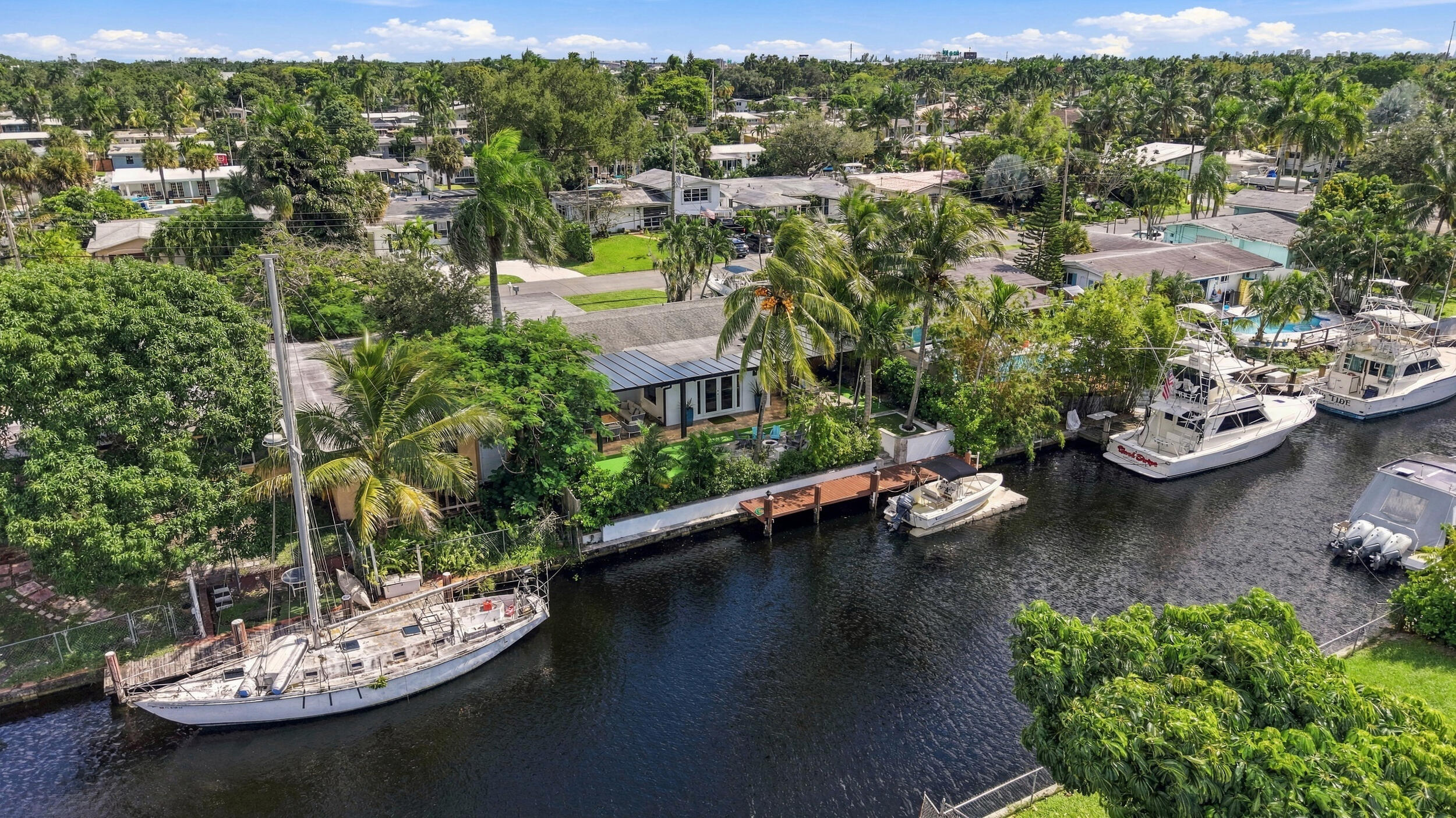 Waterfront property featuring a private boat dock, concrete bulkhead, mature palm trees, and established landscaping