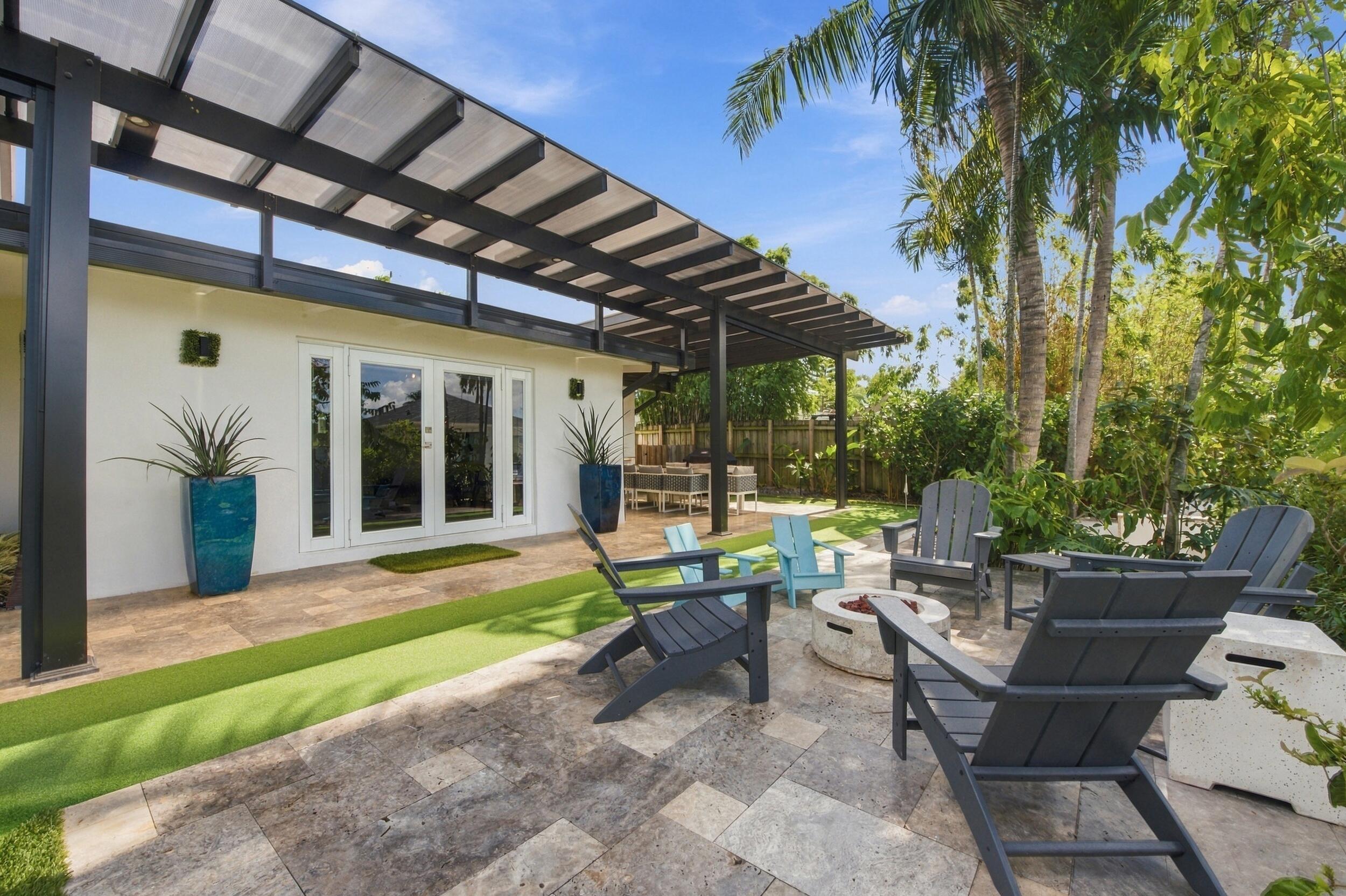 Outdoor patio featuring stone tile hardscaping, an expansive black metal pergola, and synthetic turf accent surfacing