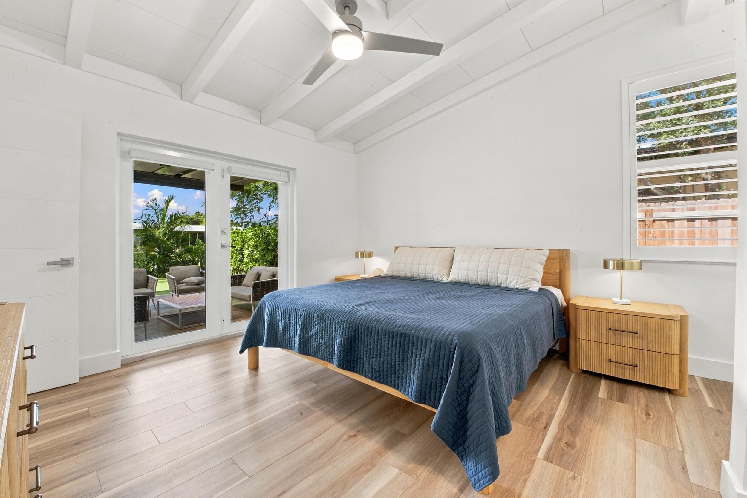 Room featuring wood-finish flooring, vaulted ceilings with exposed beams, a ceiling fan, and French doors providing exterior access