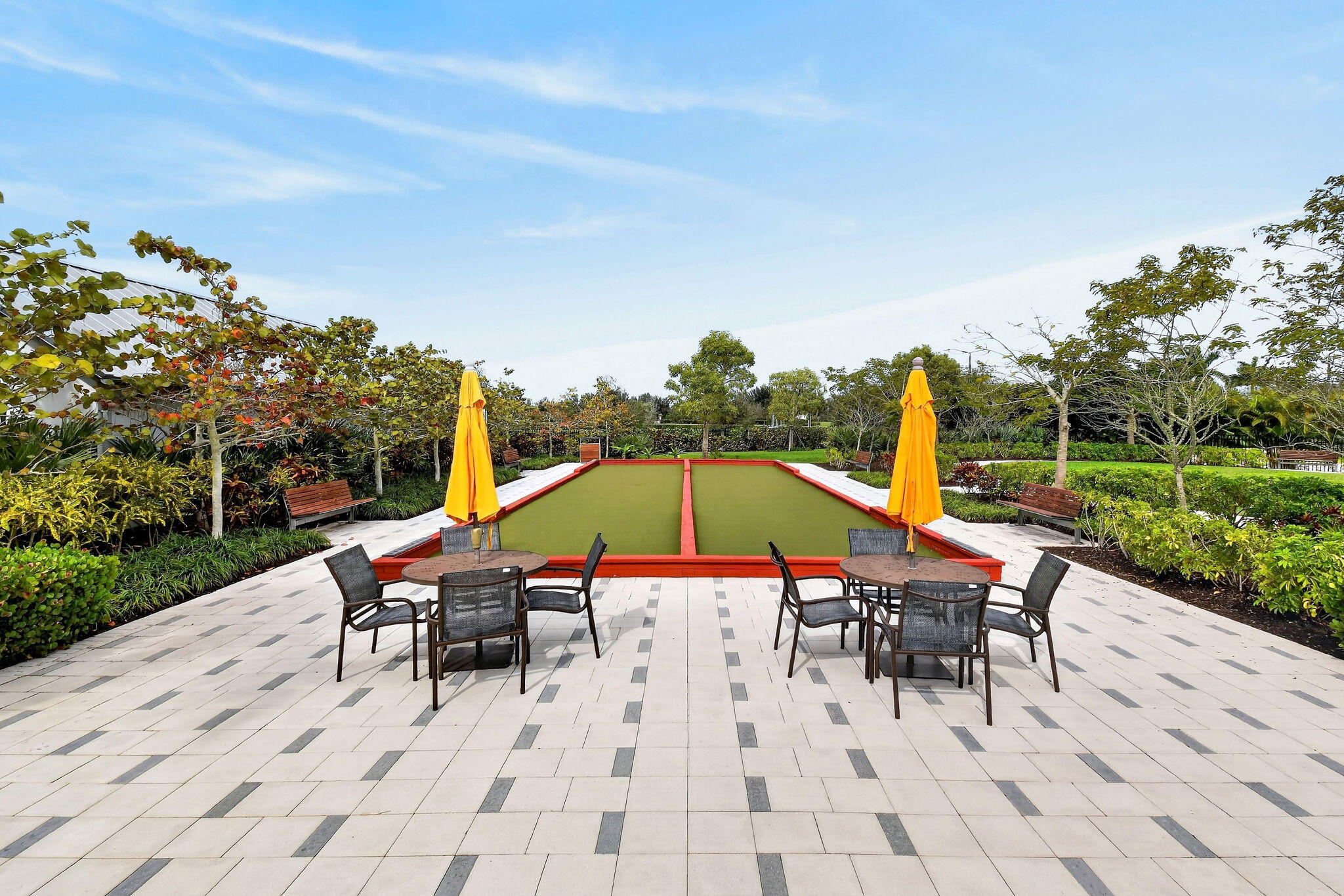 Expansive outdoor amenity space with a bocce ball court and patterned paver patio