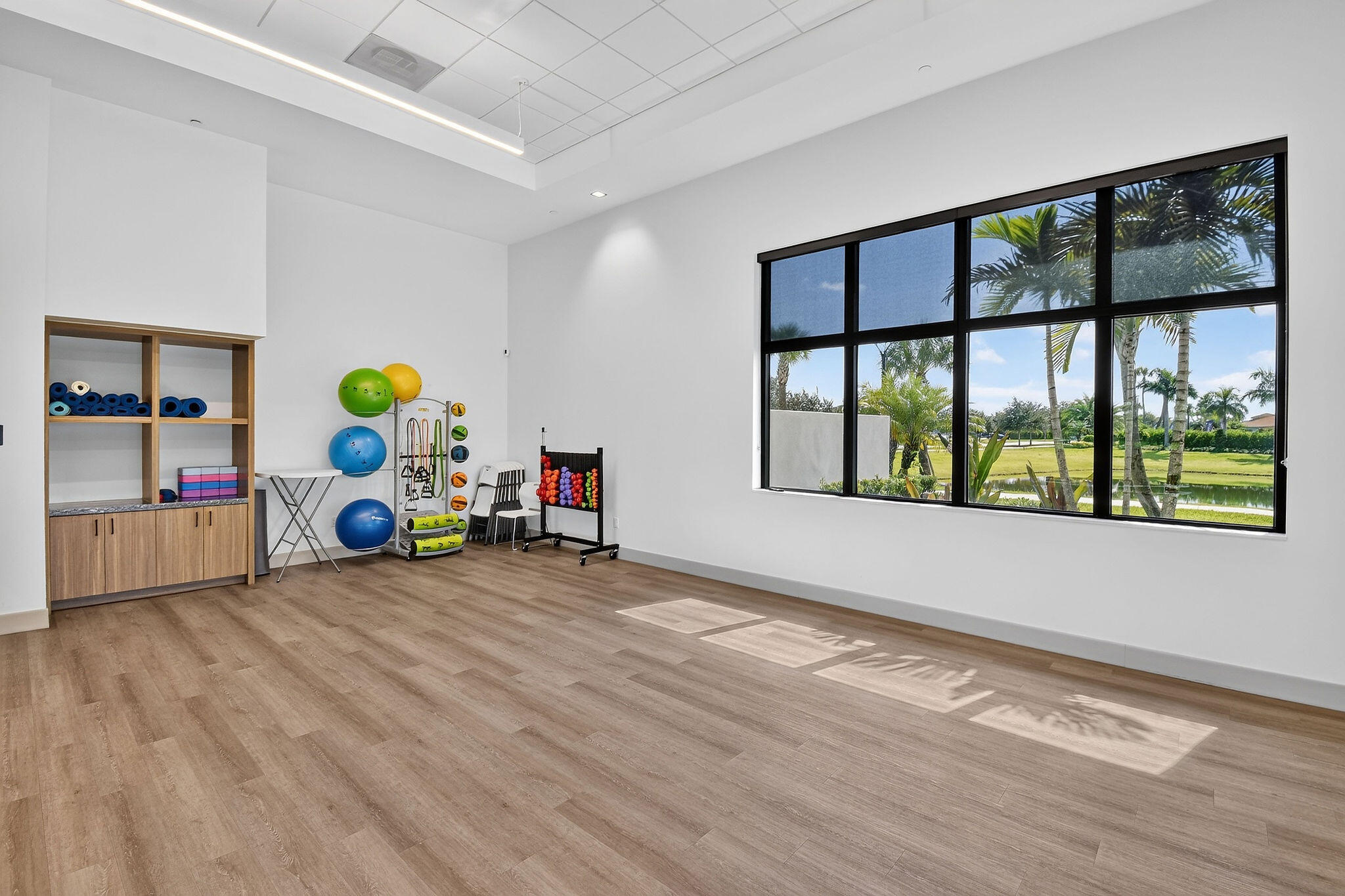 Spacious room featuring large format windows, wood-finish flooring, built-in shelving with lower cabinetry, and recessed lighting