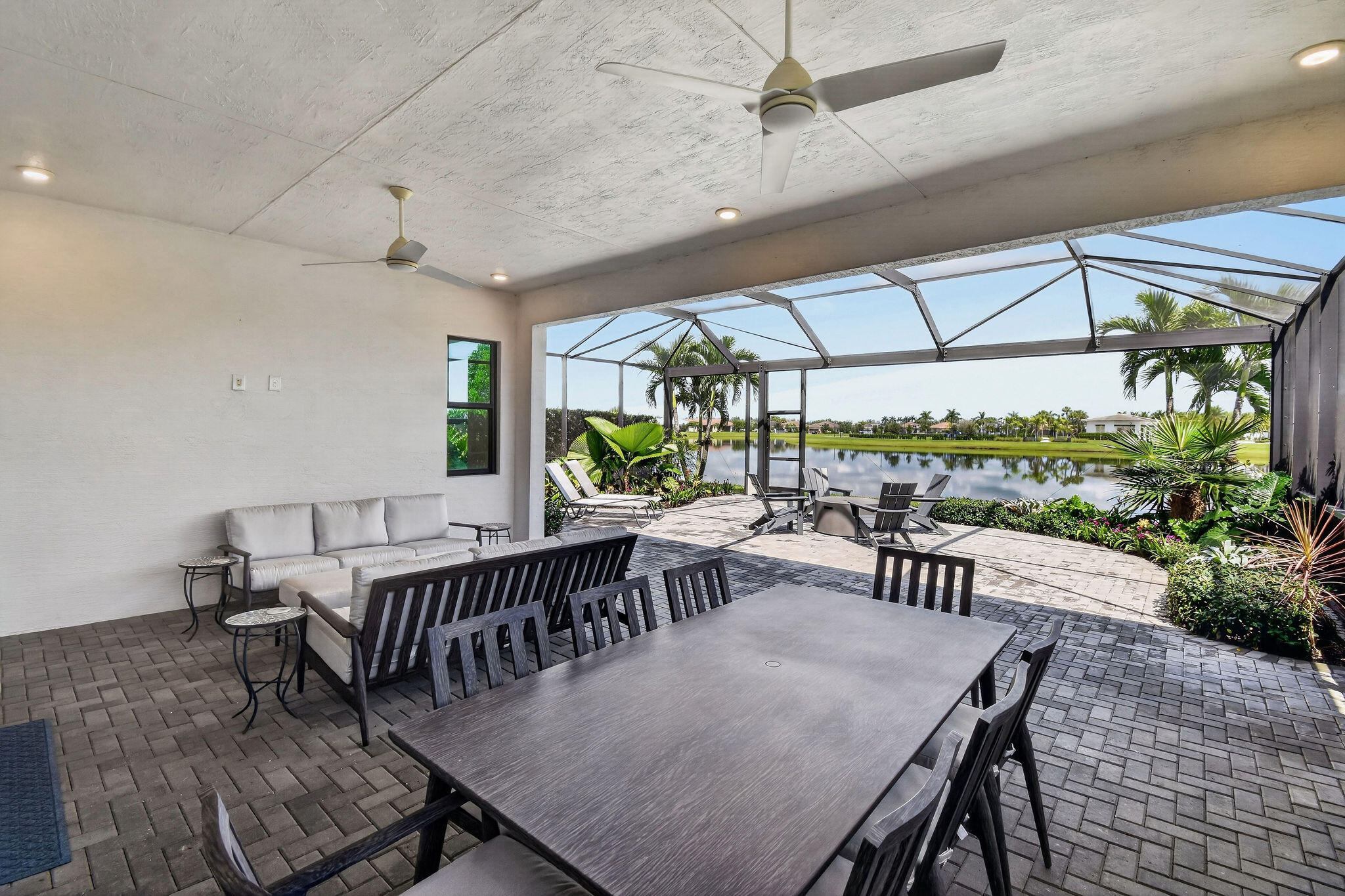 Screened lanai featuring a paver patio, ceiling fans, recessed lighting, and a water backdrop