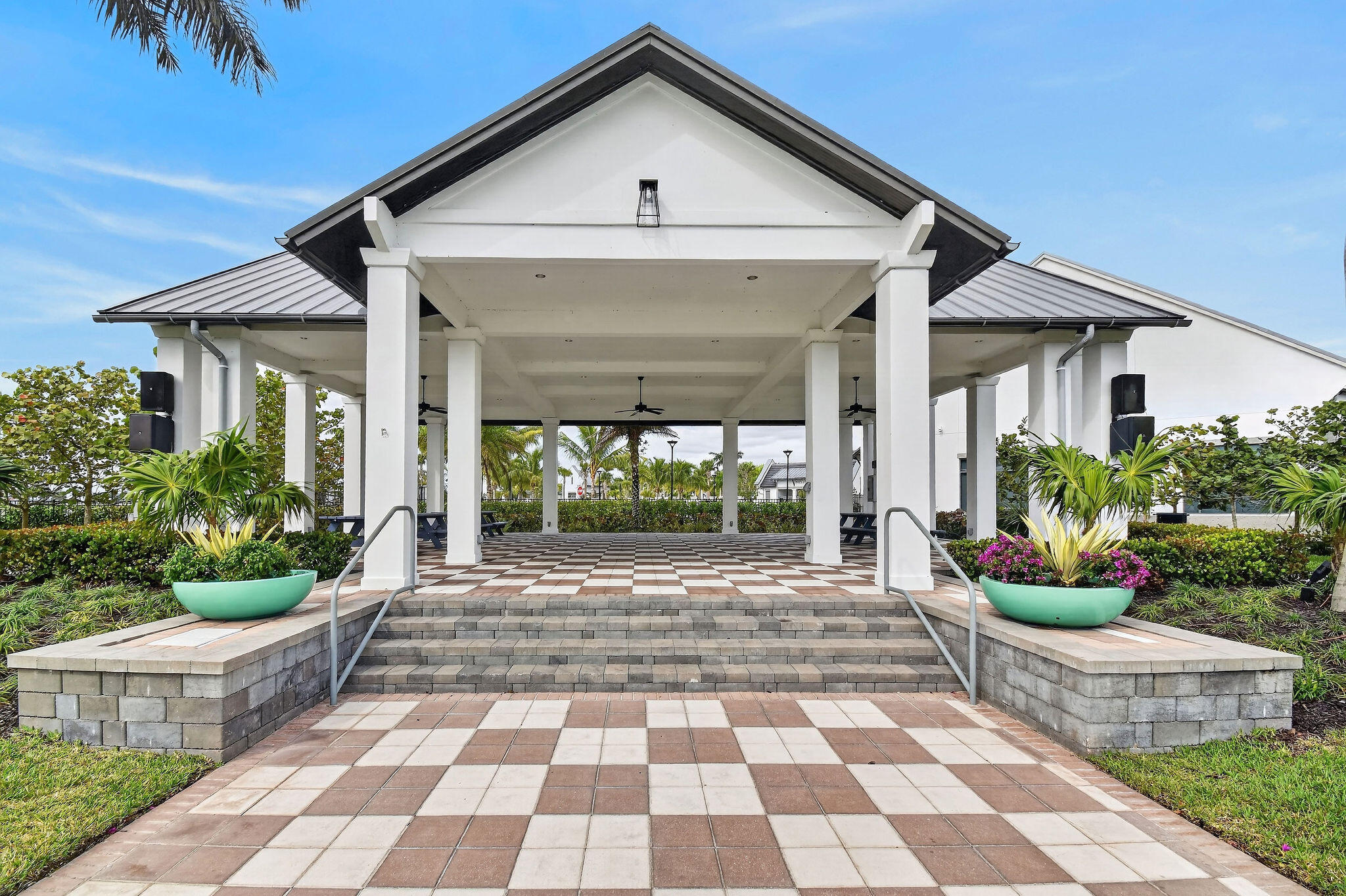 Expansive covered patio featuring a gabled roofline, checkerboard paver flooring, and multiple support columns