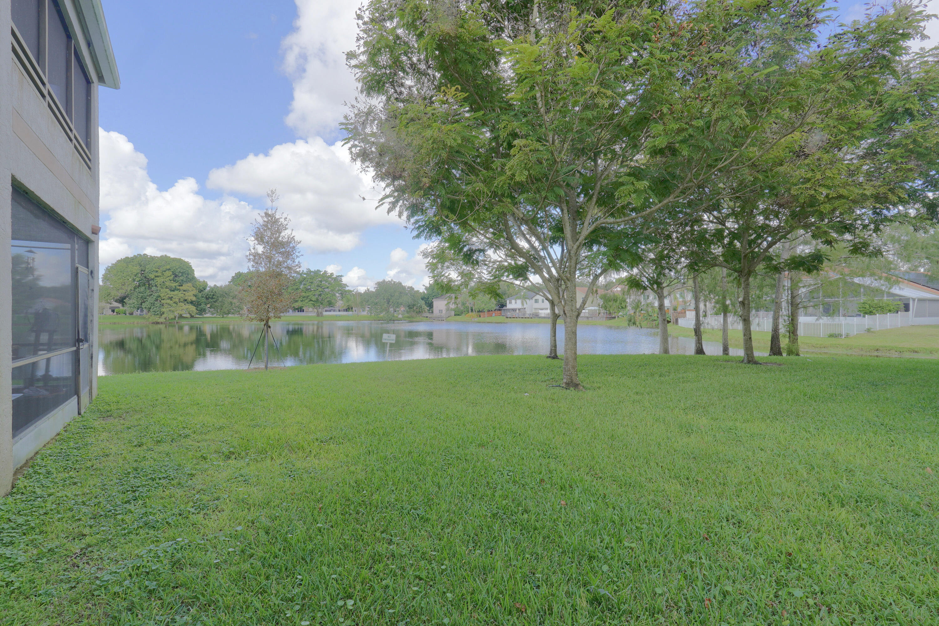 Waterfront lot featuring a screened-in lanai, mature trees, and an expansive lawn Waterfront lot featuring a screened-in lanai, mature trees, and an expansive lawn