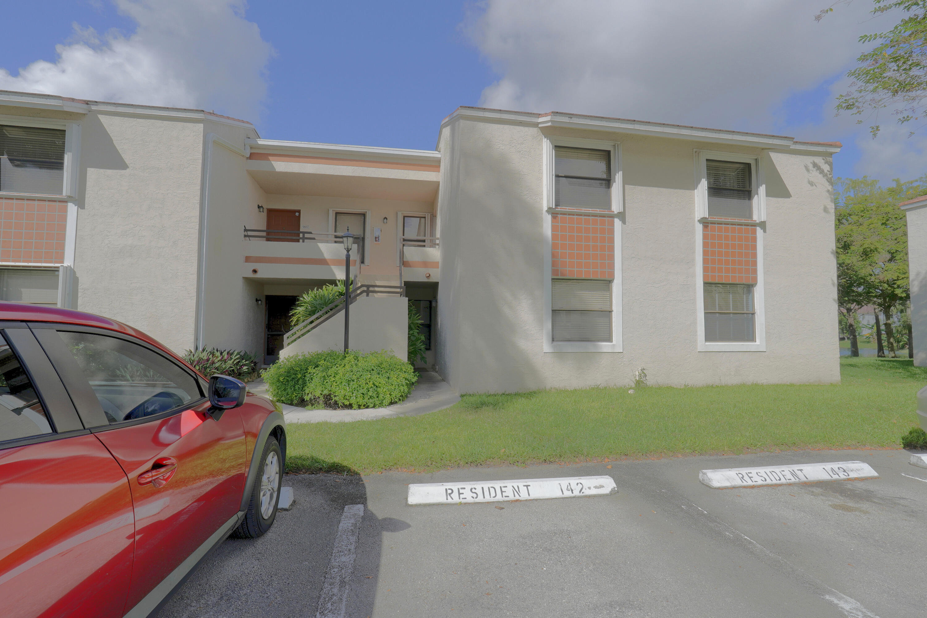 Two-story stucco exterior featuring tile accents, sliding windows, and designated resident parking Two-story stucco exterior featuring tile accents, sliding windows, and designated resident parking