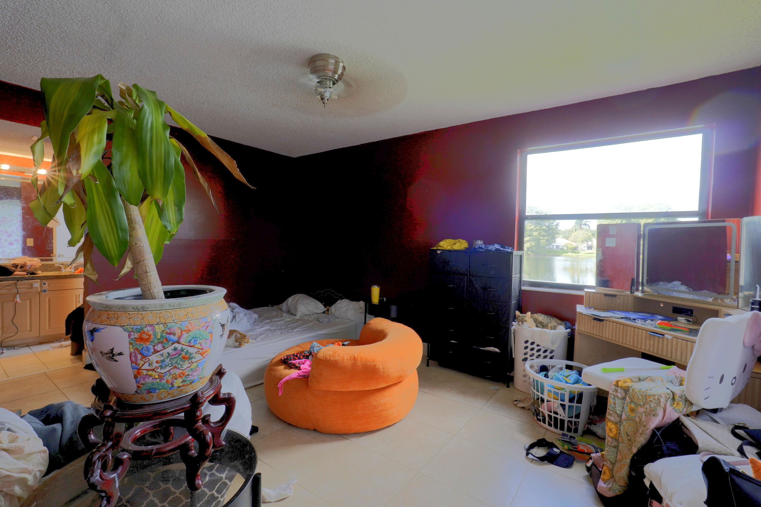 Spacious room featuring large window with exterior water frontage, neutral tile flooring, and a ceiling-mounted light fixture Spacious room featuring large window with exterior water frontage, neutral tile flooring, and a ceiling-mounted light fixture