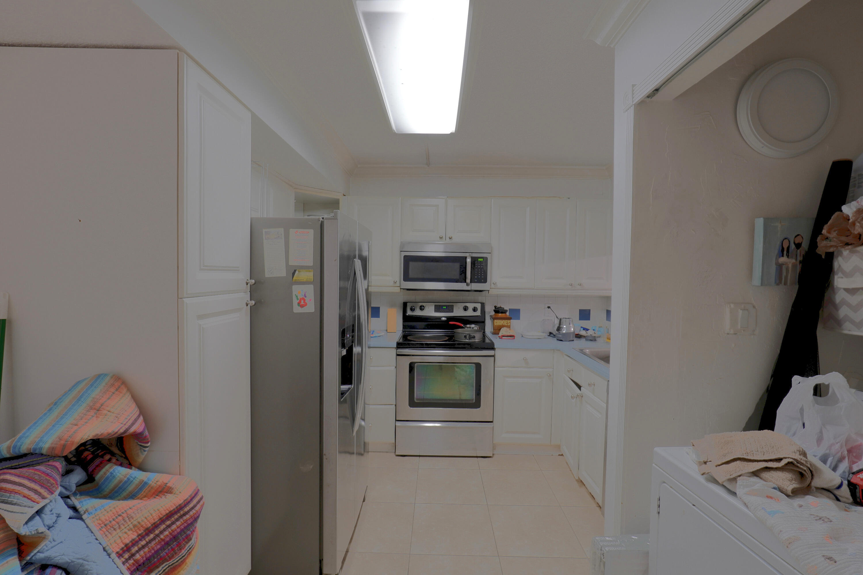 Kitchen featuring white cabinetry, stainless steel appliances, tiled backsplash, and light-toned flooring Kitchen featuring white cabinetry, stainless steel appliances, tiled backsplash, and light-toned flooring