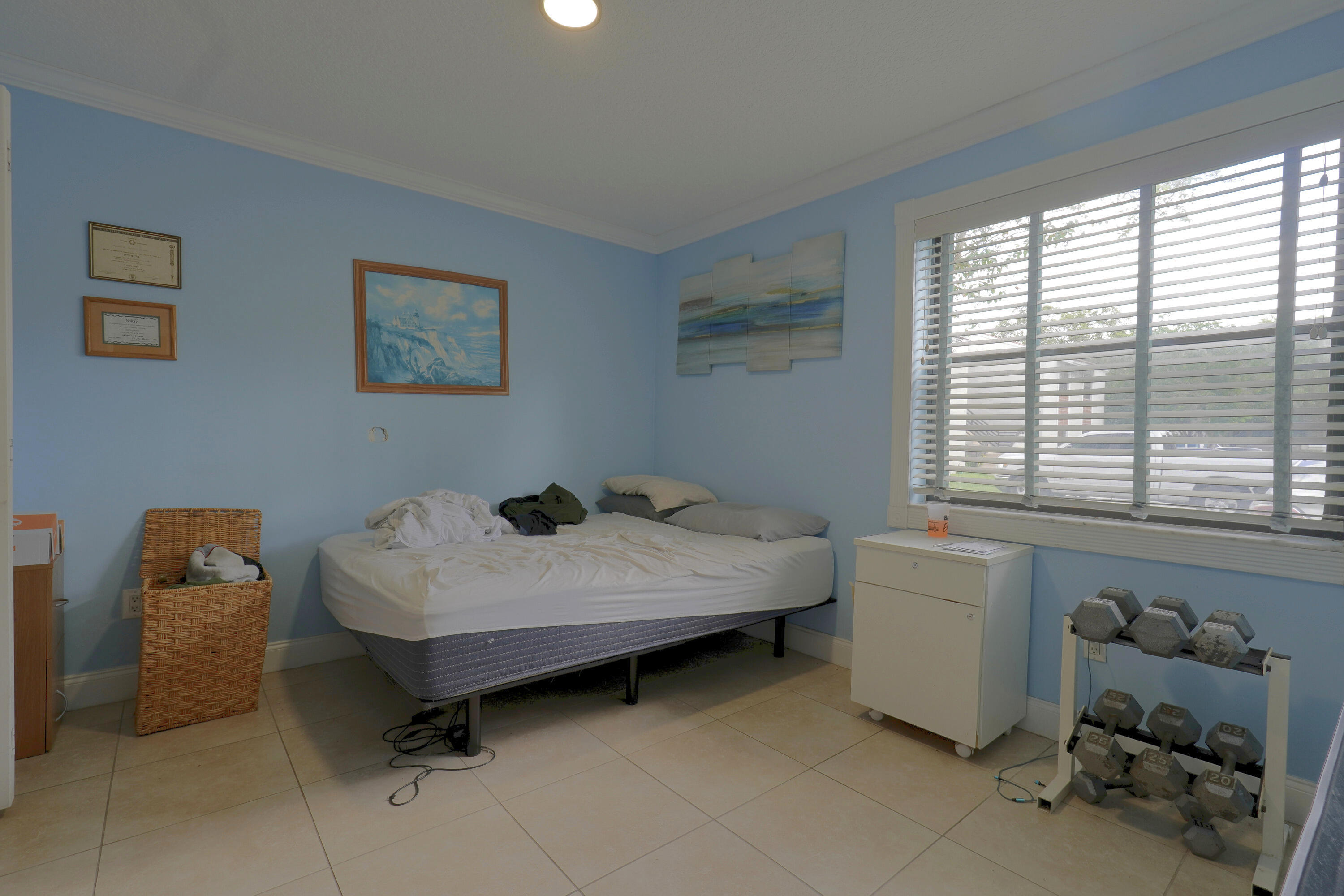 Light-filled room featuring large-format tile flooring, crown molding, and horizontal slat window blinds